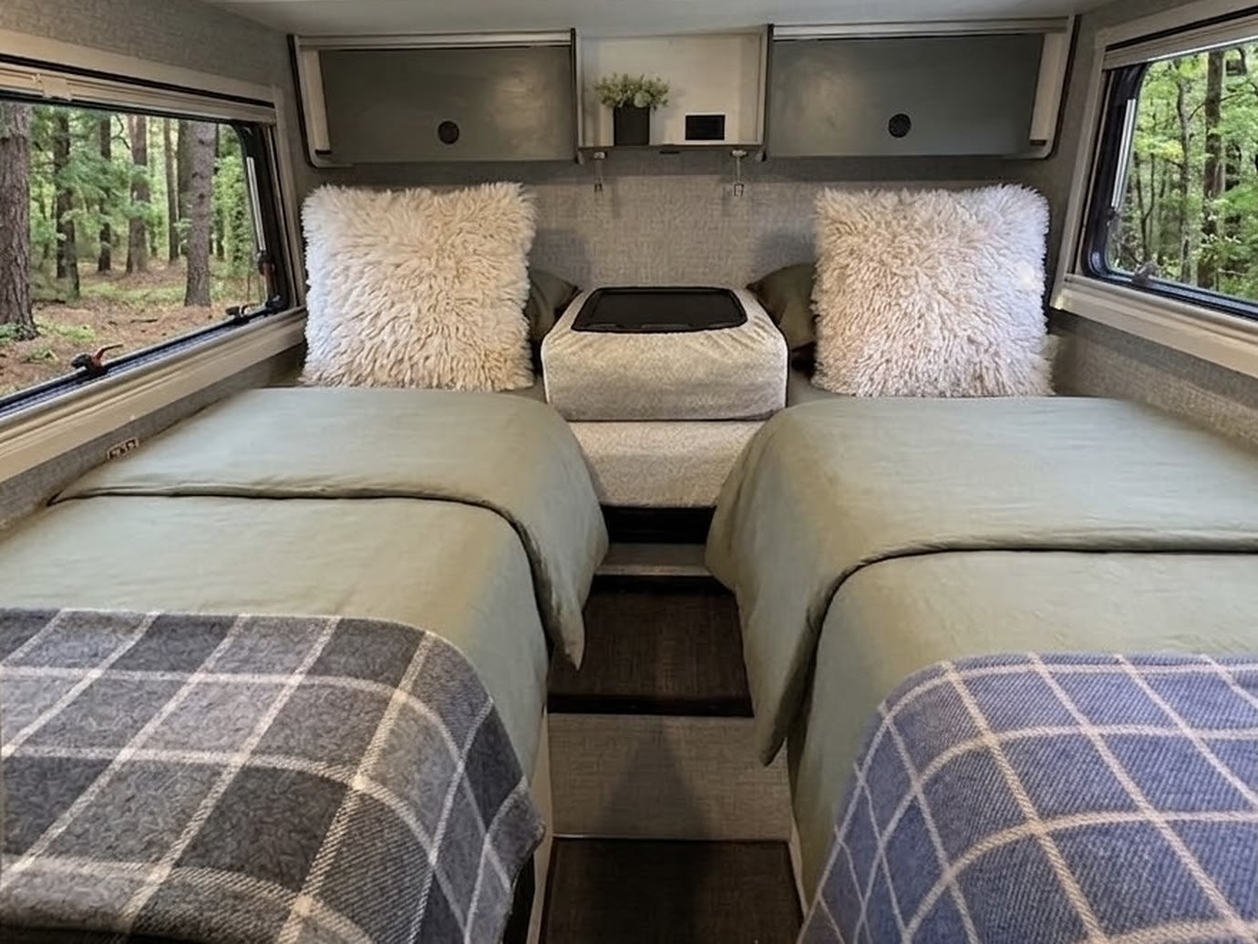Cozy RV rental interior with two single beds, fluffy pillows, and forest views from large windows.. Winnebago Ekko 2025