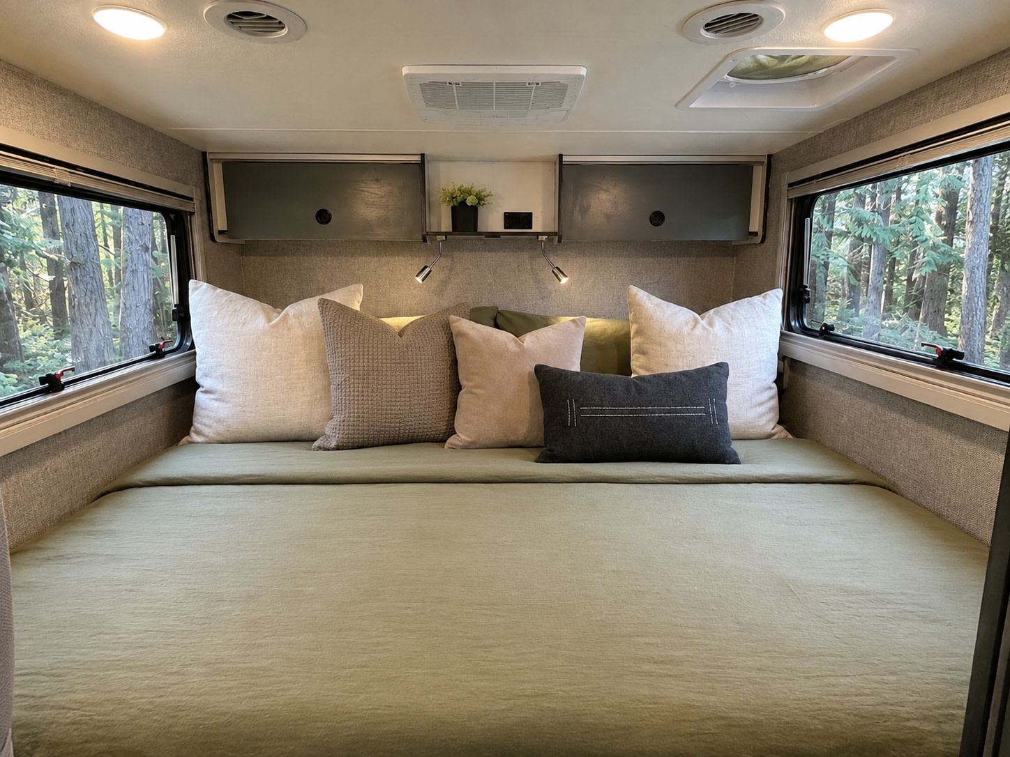 Spacious RV rental bedroom showcasing a bed with green bedding, cozy pillows, and clear forest views from large windows.. Winnebago Ekko 2025