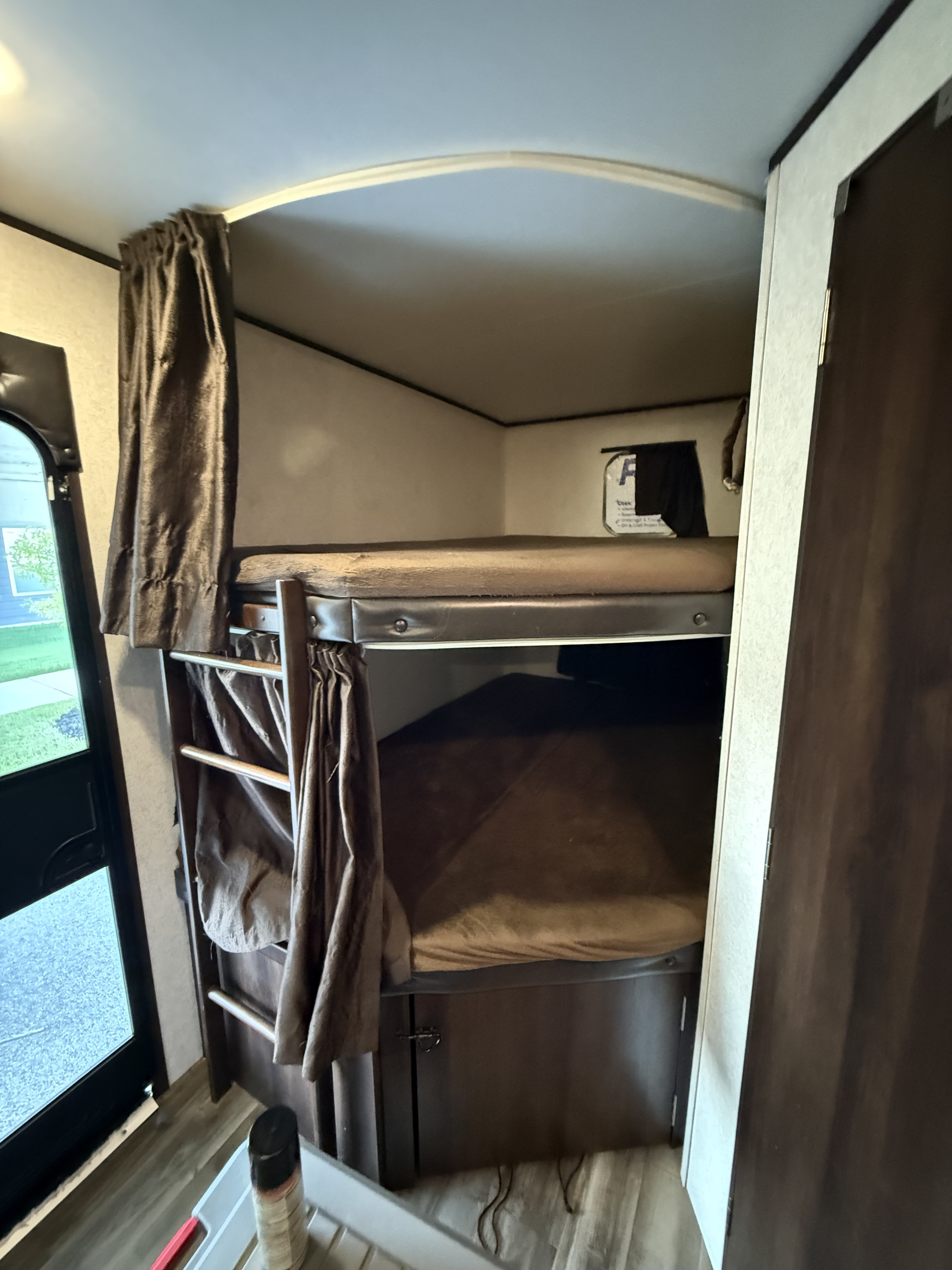 Cozy bunk beds inside an RV rental, featuring a ladder and privacy curtains, perfect for family travel adventures.. Jayco Jay Flight SLX Rocky Mountain Edition 2020