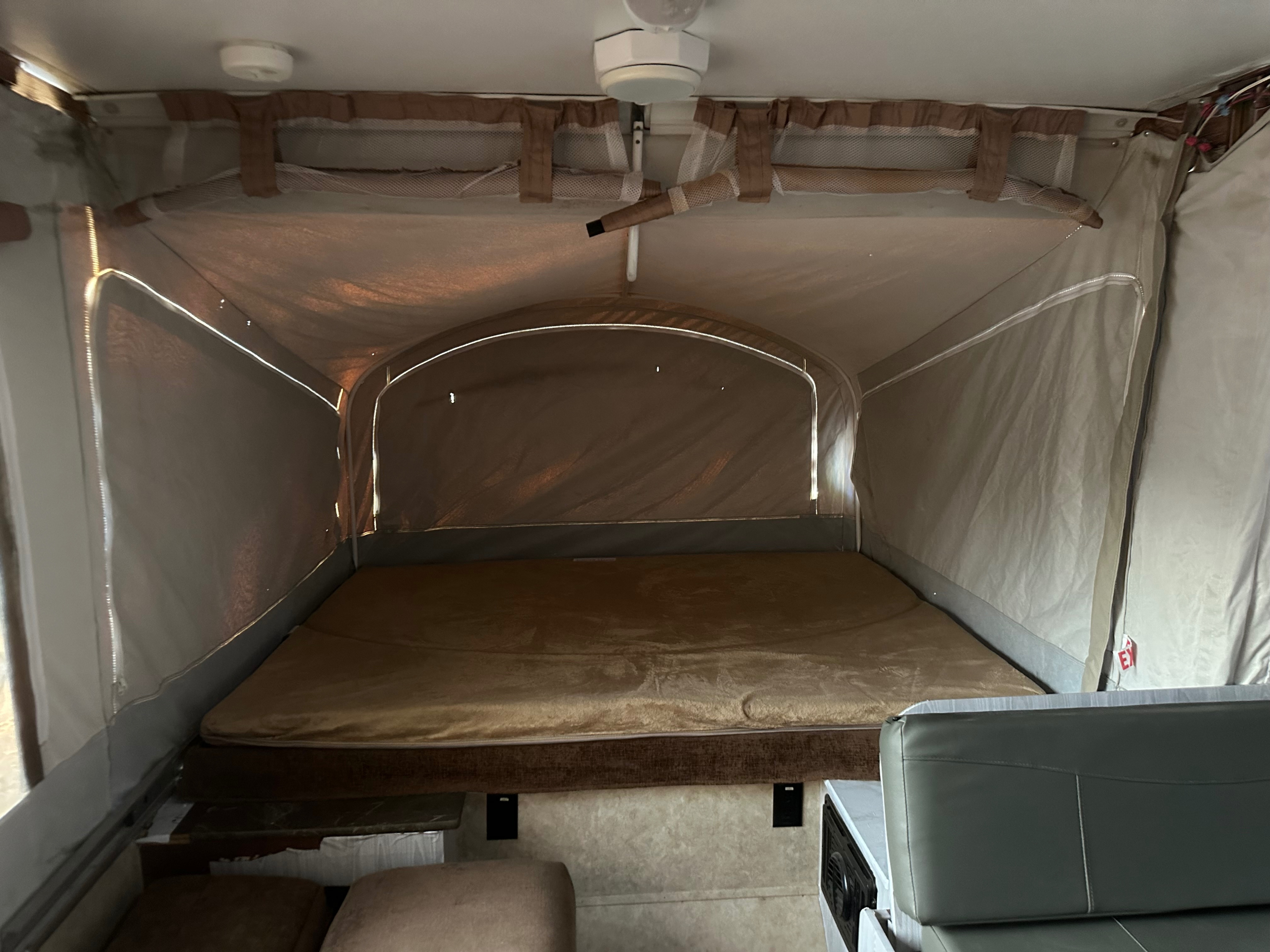 Pop-up camper rv rental interior: the main sleeping bed, light-filtering tent walls, and partial seating.. Jayco 1209SC 2016
