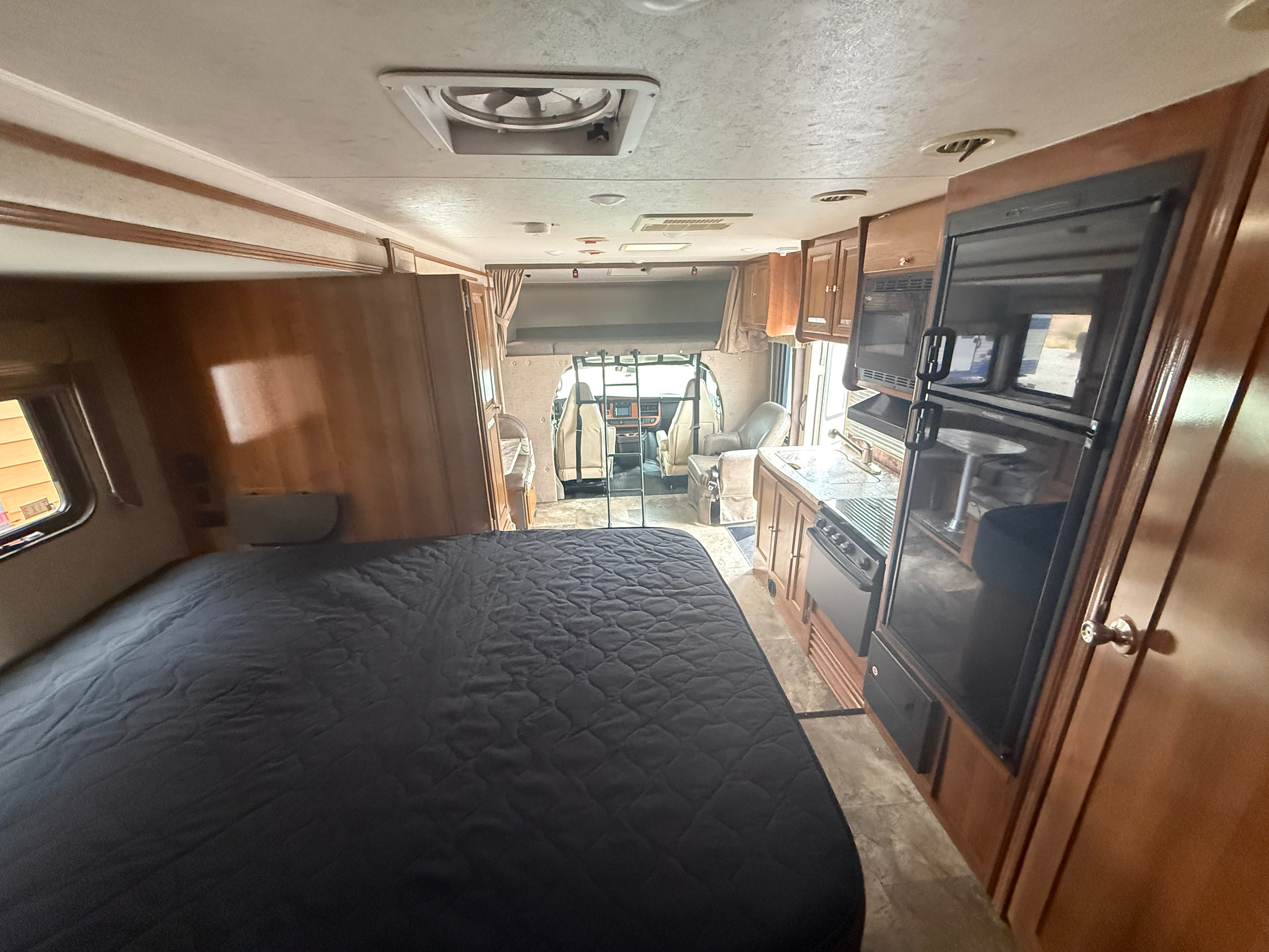 Experience comfort in this RV rental! View from the main bed shows a full kitchen, fridge, and front cockpit.. Coachmen Leprechaun 240FS 2018