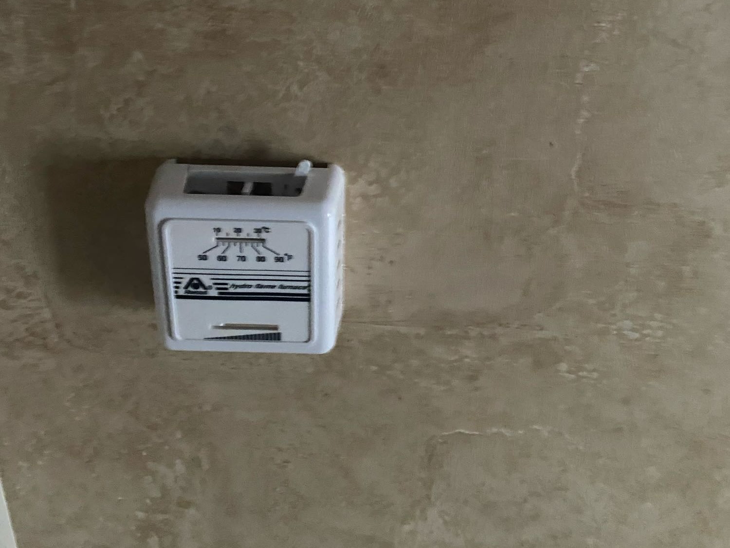 White thermostat on textured wall in RV rental, showing F/C temperature scales for HVAC control.. Jayco Jay Feather Ultra Lite 2012