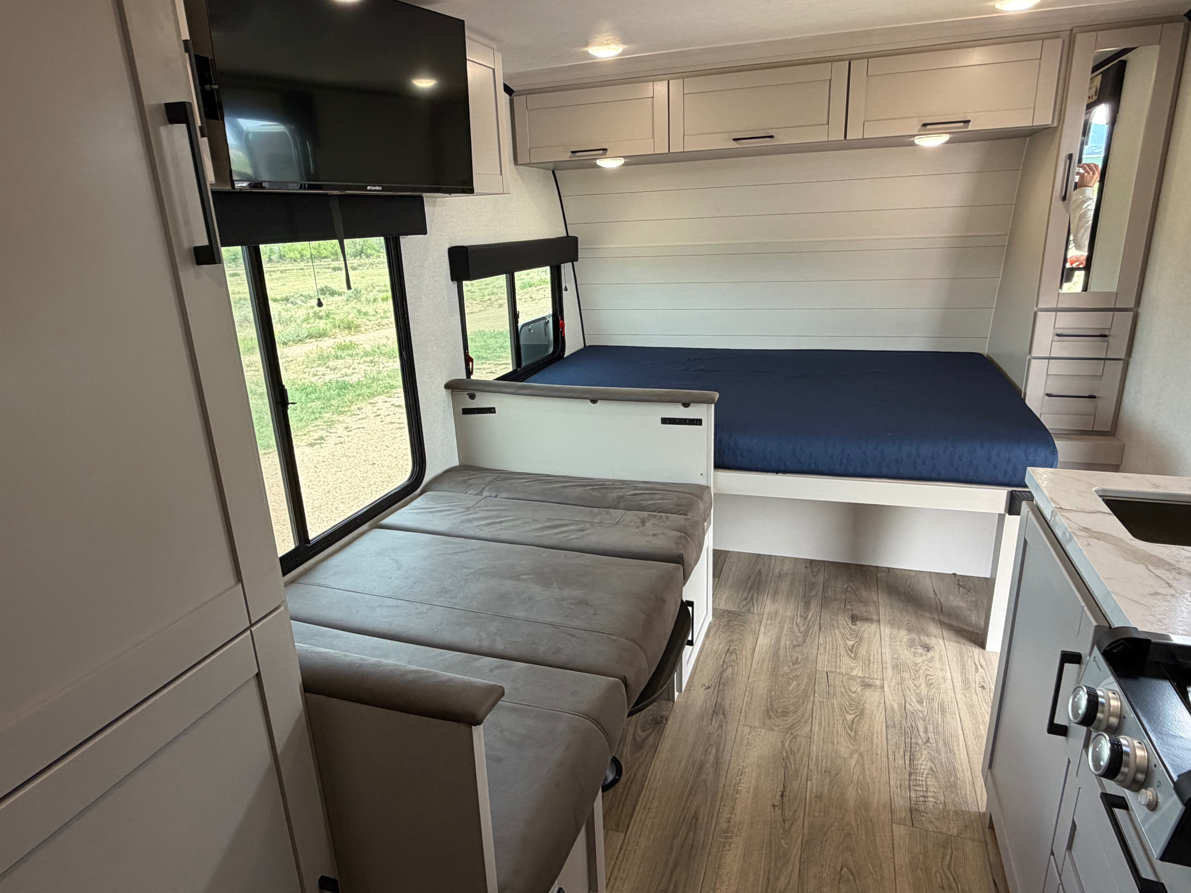 Modern RV rental interior showing a master bed, convertible dinette, kitchen, and TV. Comfort for your road trip.. Jayco Jay Feather Air 2026