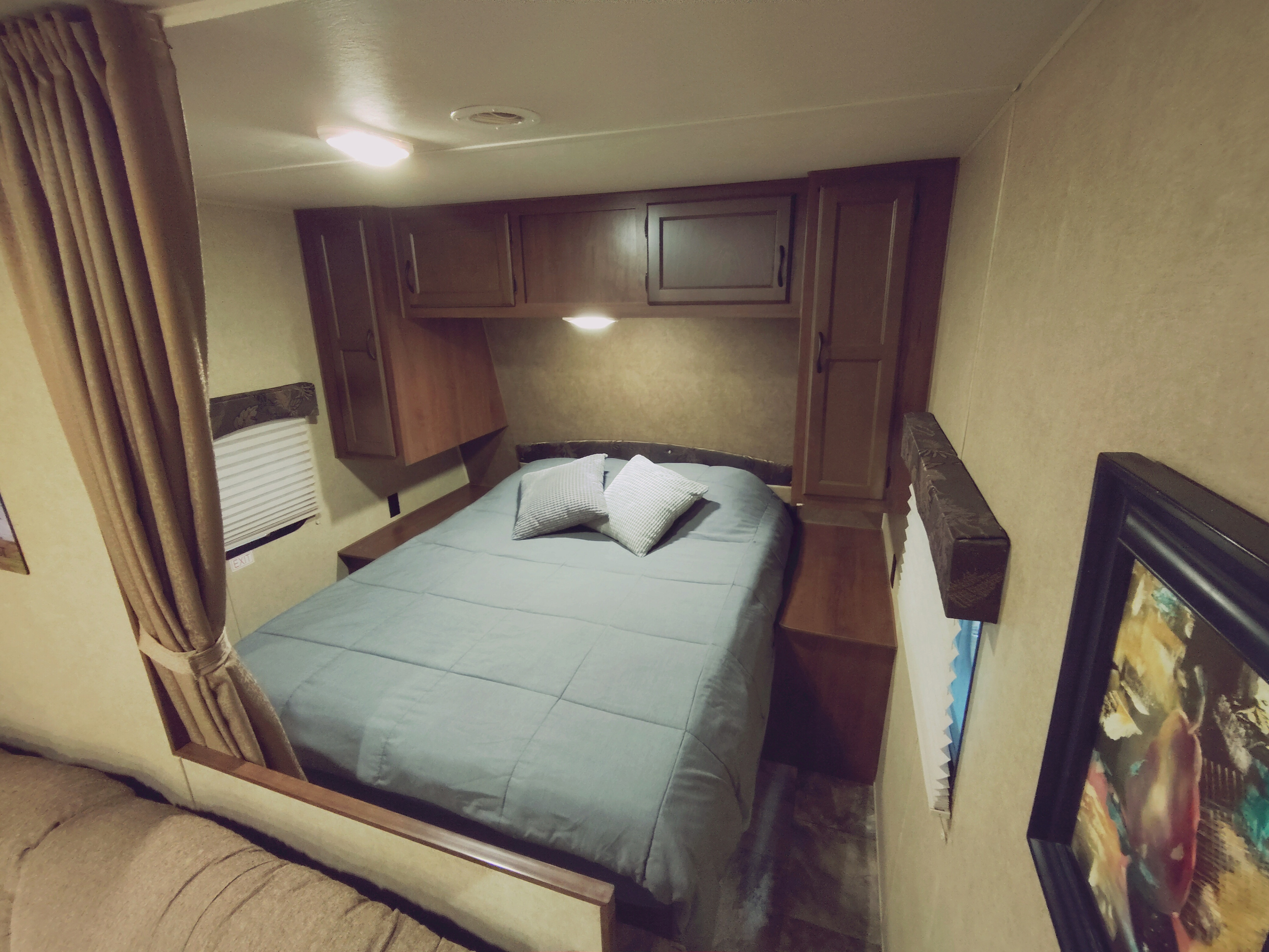 Cozy rv rental bedroom features a queen bed, overhead cabinets, a window with blinds, and soft lighting.. Jayco Jay Flight Swift 2014