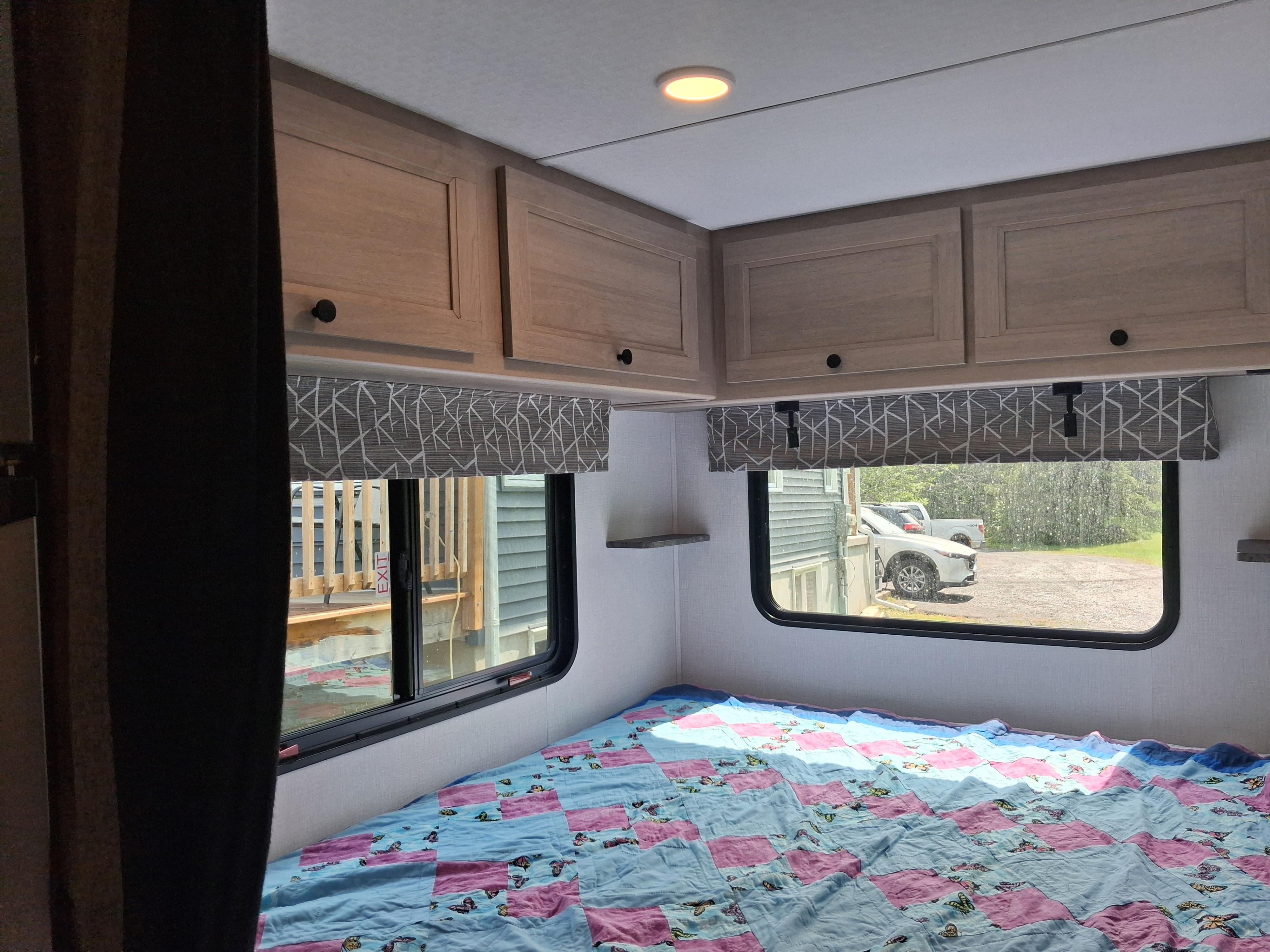 Cozy RV rental bedroom featuring light wood cabinets, windows with valances, and a blue/pink butterfly quilt on the bed.. FOREST RIVER SL 2150LE 2027