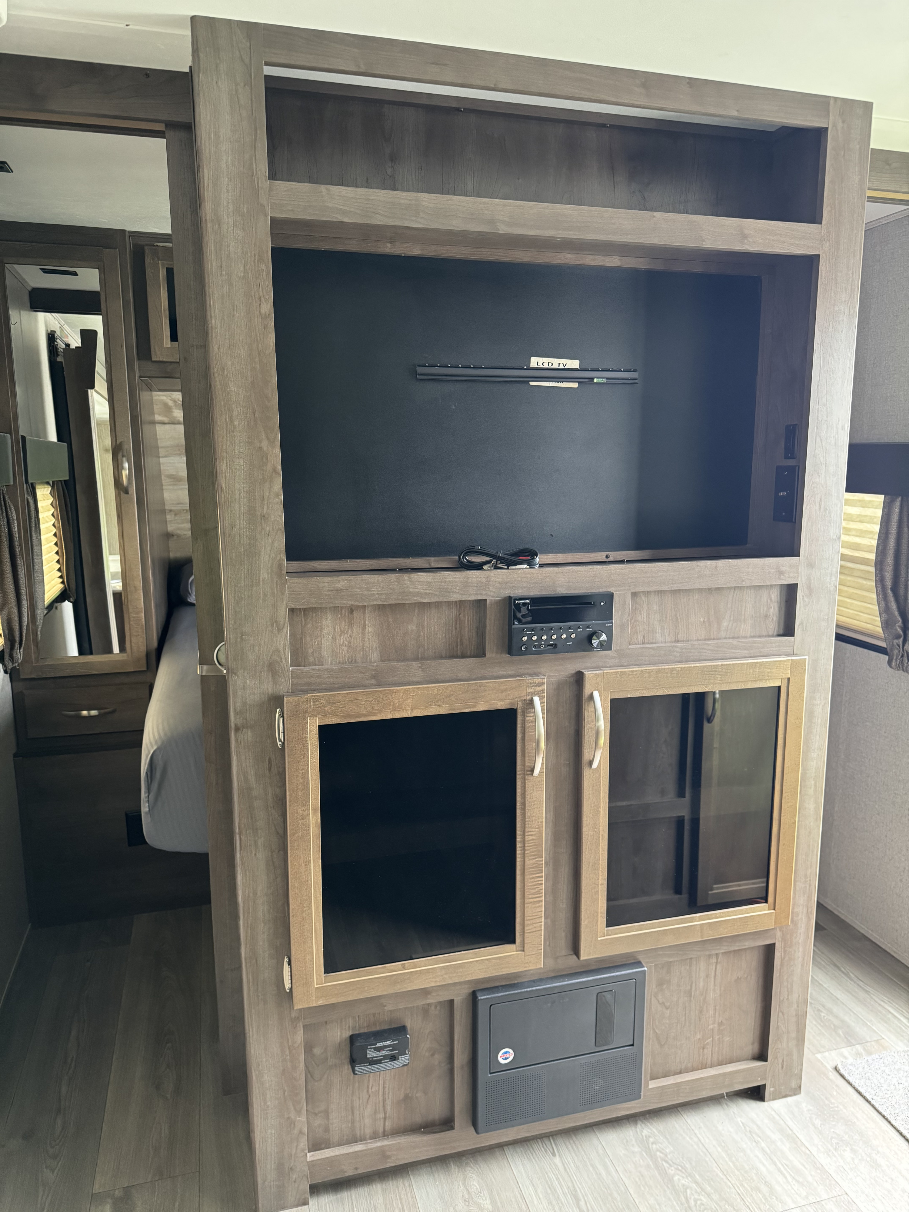 This RV rental's built-in entertainment center features a TV mount, stereo, and glass-front cabinets in a modern wood finish.. Dutchmen Coleman Light 2019