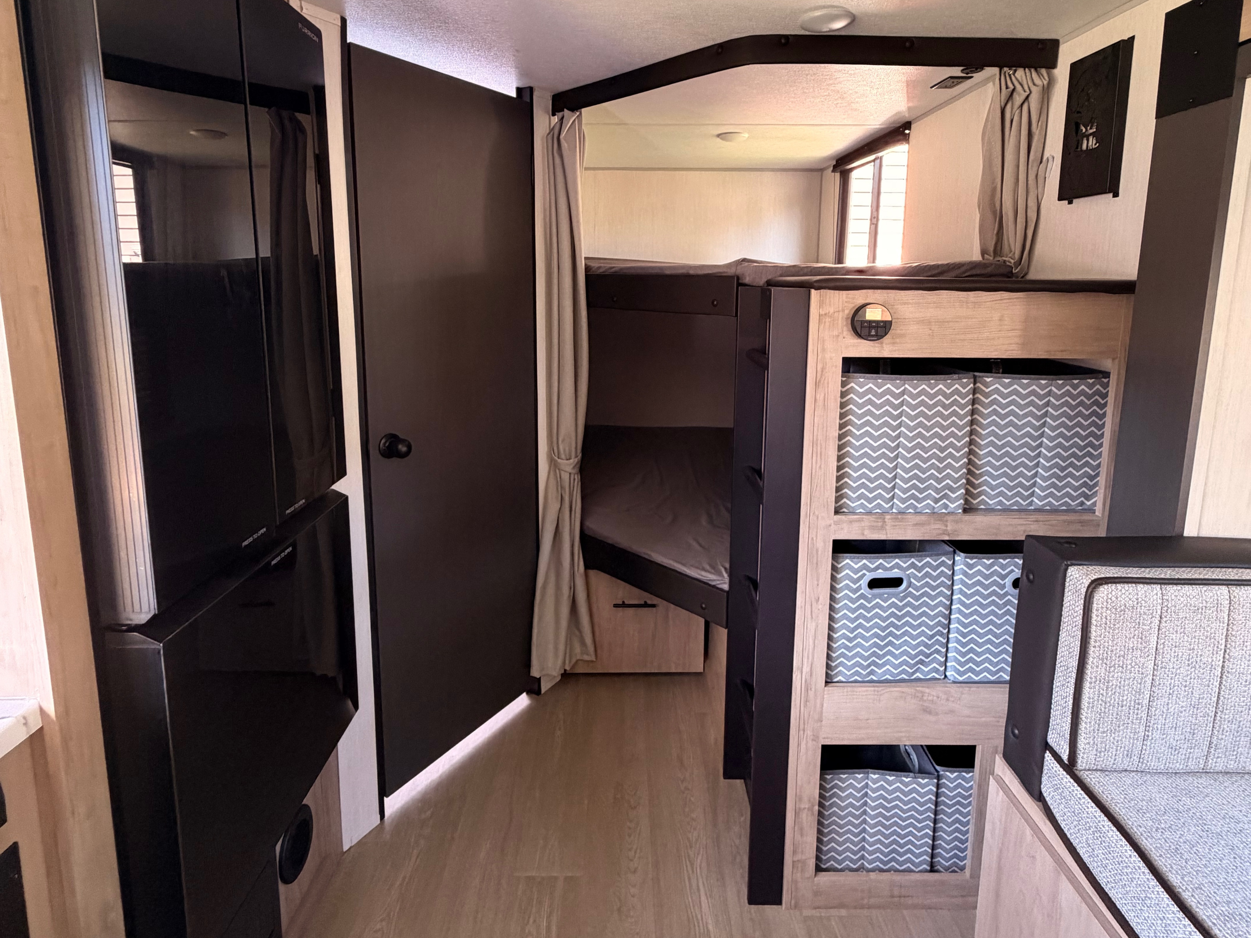 Interior of an rv rental with bunk beds, storage bins, and a dinette area, showcasing a compact and functional living space.. Forest River Campsite Reserve 2026