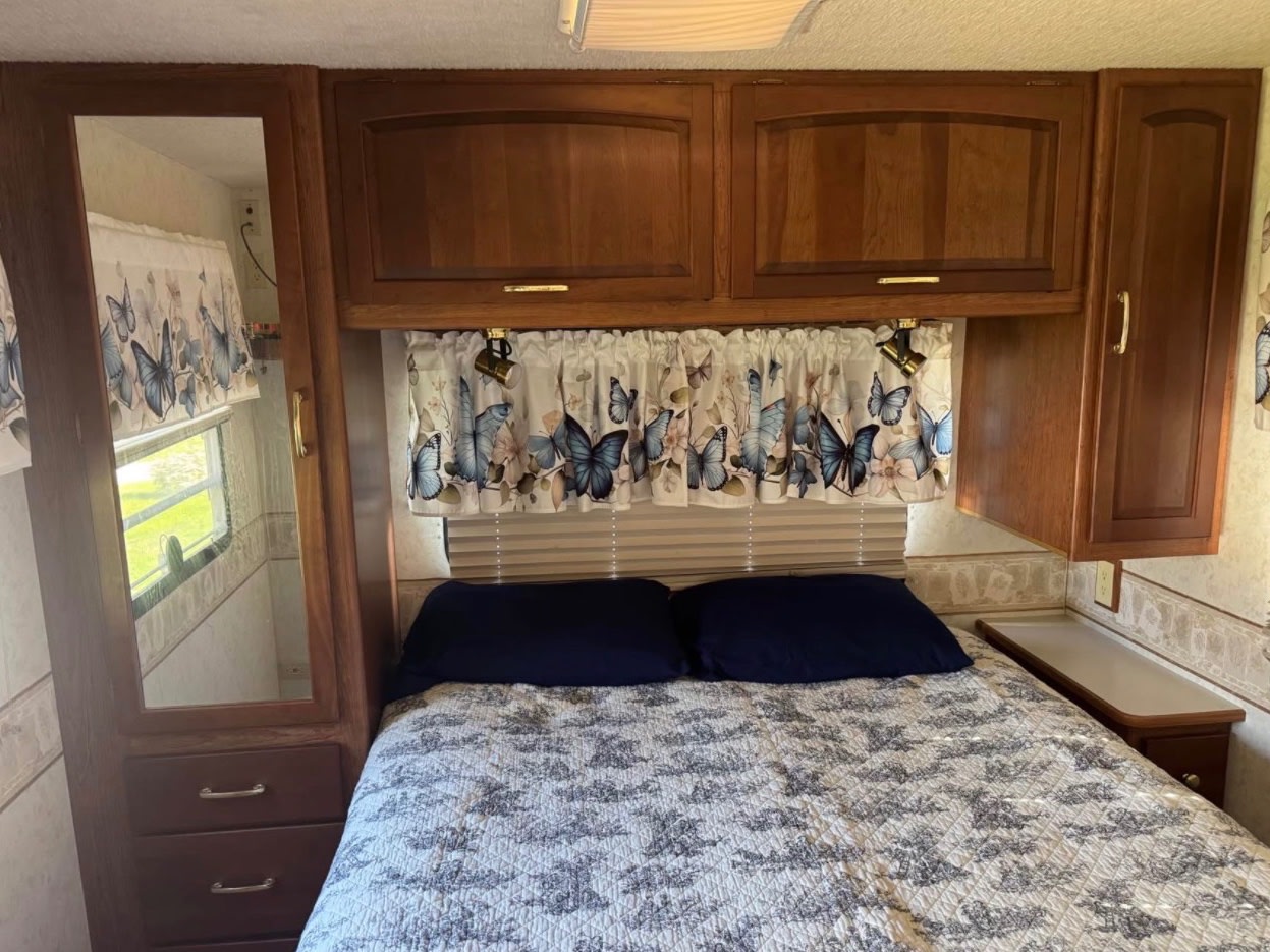 RV rental interior: Bedroom with a comfortable bed, overhead cabinets, and a mirrored wardrobe.. Winnebago Itasca 2001