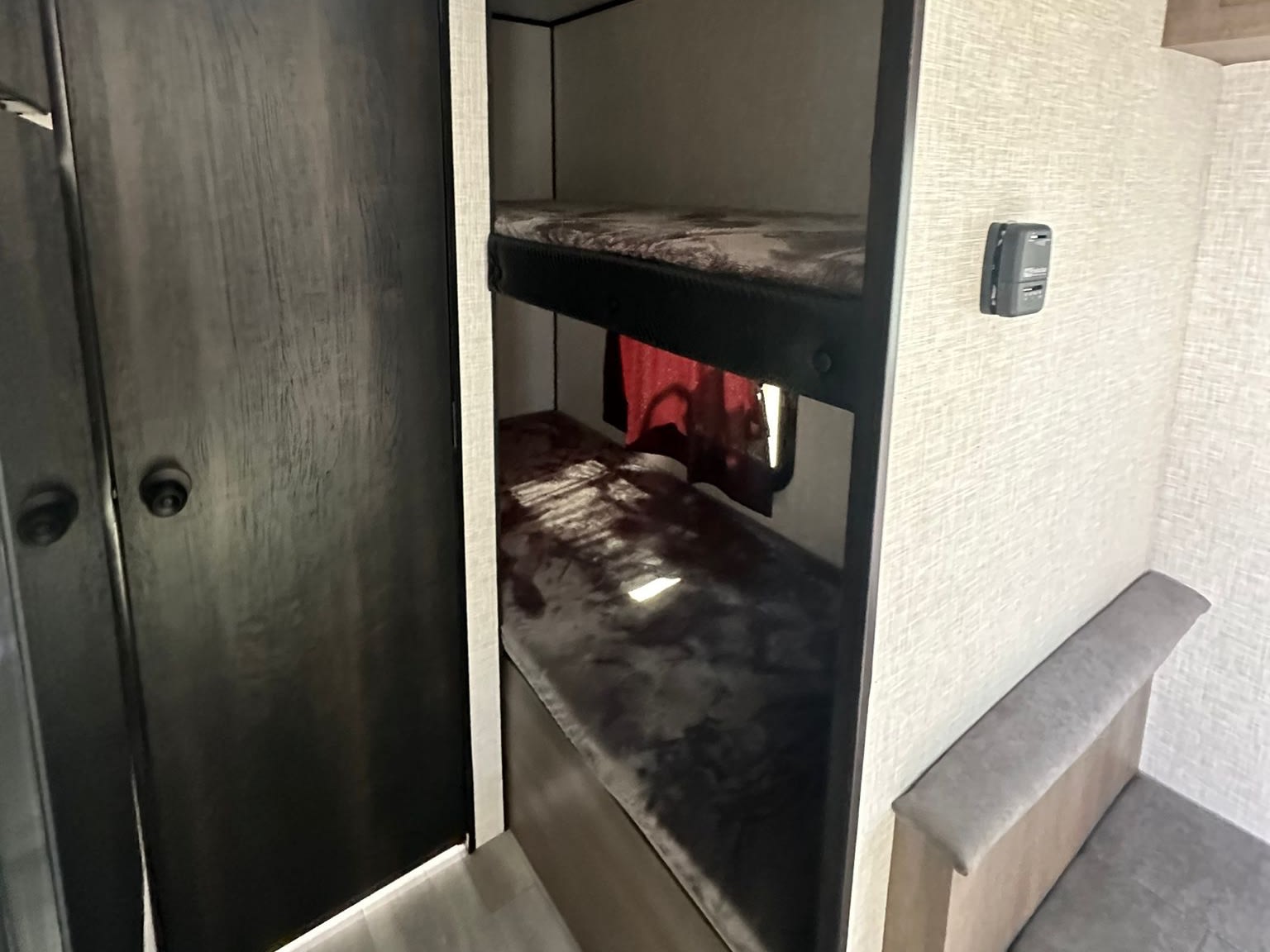 RV rental interior: two dark bunk beds, a light gray dinette, and a door, designed for a comfortable camper stay.. Jayco Jay Flight SLX 2024