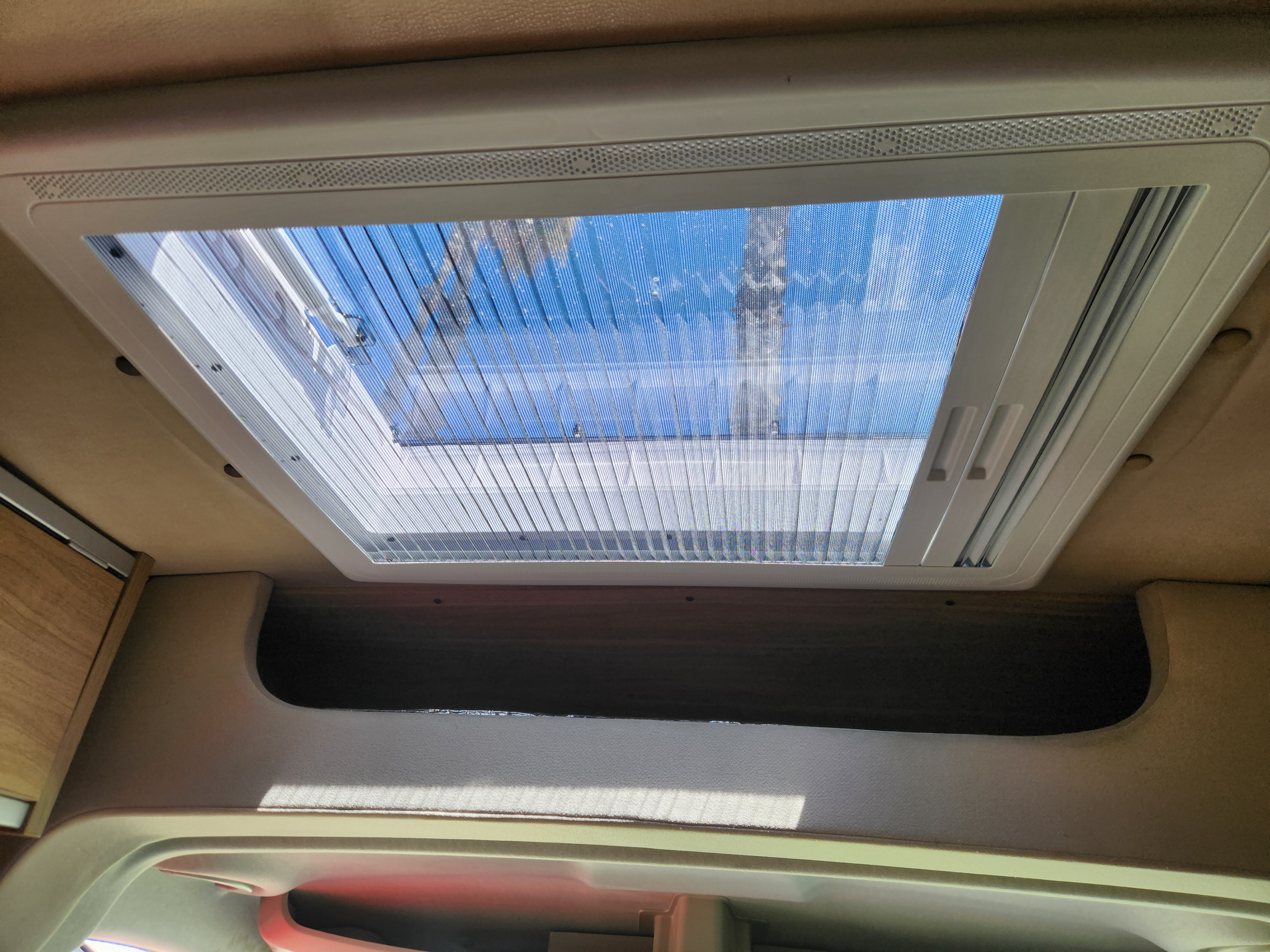 Bright rv rental interior view of a roof vent/skylight with a pull-across mesh screen, revealing blue sky above.. RAM ProMaster 3500 2016