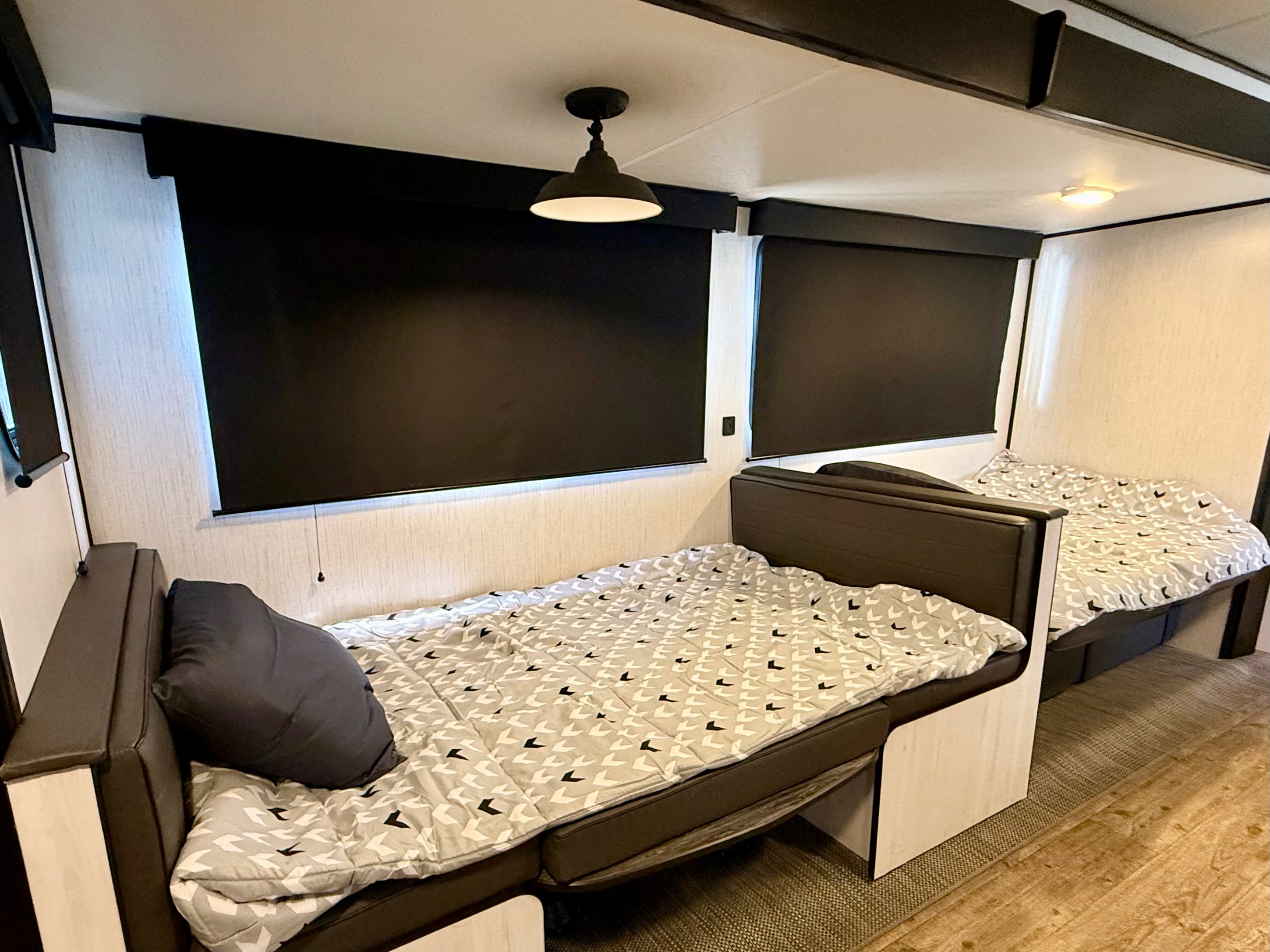 Cozy RV rental interior with two bunk beds featuring patterned bedding, dark blinds, and ambient lighting.. Heartland RVs Trail Runner 2022