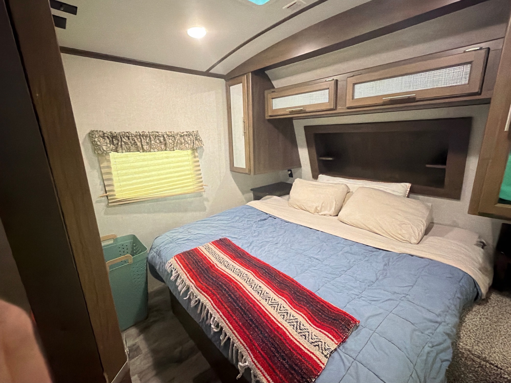 Cozy RV rental bedroom with a comfortable bed, overhead storage, and window, perfect for your travel.. Keystone RV Cougar 2019