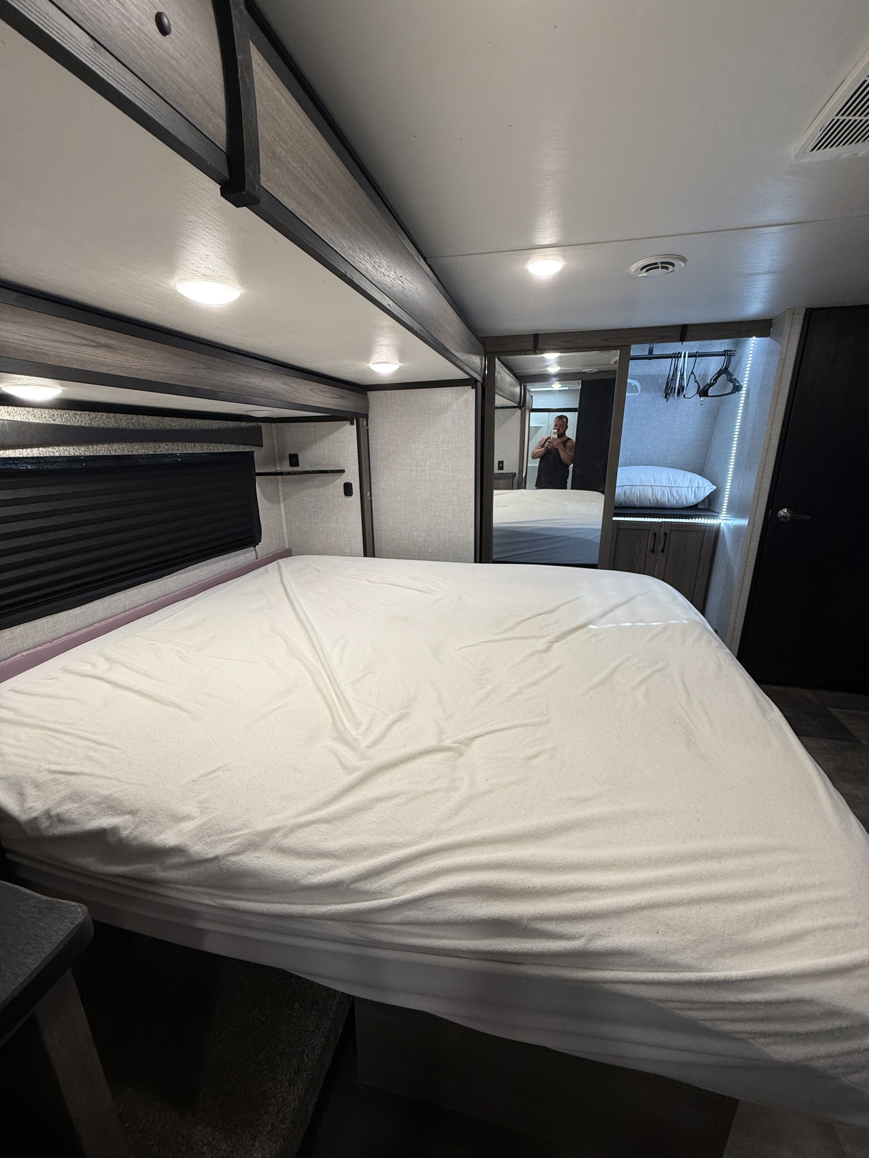 Cozy rv rental bedroom featuring a spacious bed with white sheets, and a mirrored closet reflecting the person taking the photo.. Crossroads RV Cameo 2022
