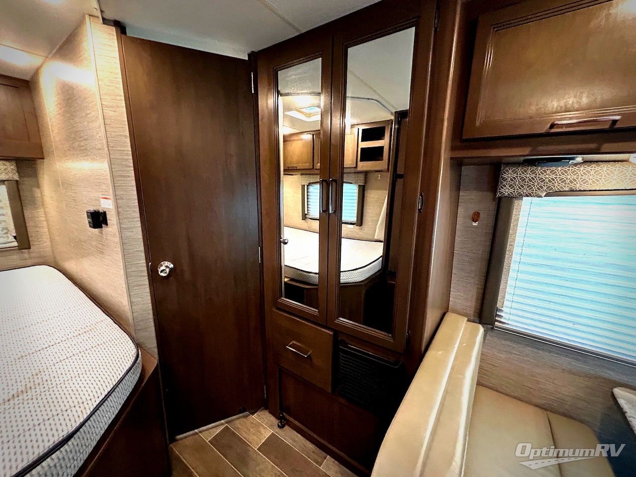 Explore this rv rental interior, featuring a cozy bed, mirrored wardrobe, and a comfortable dinette with a window.. Thor Chateau 2020