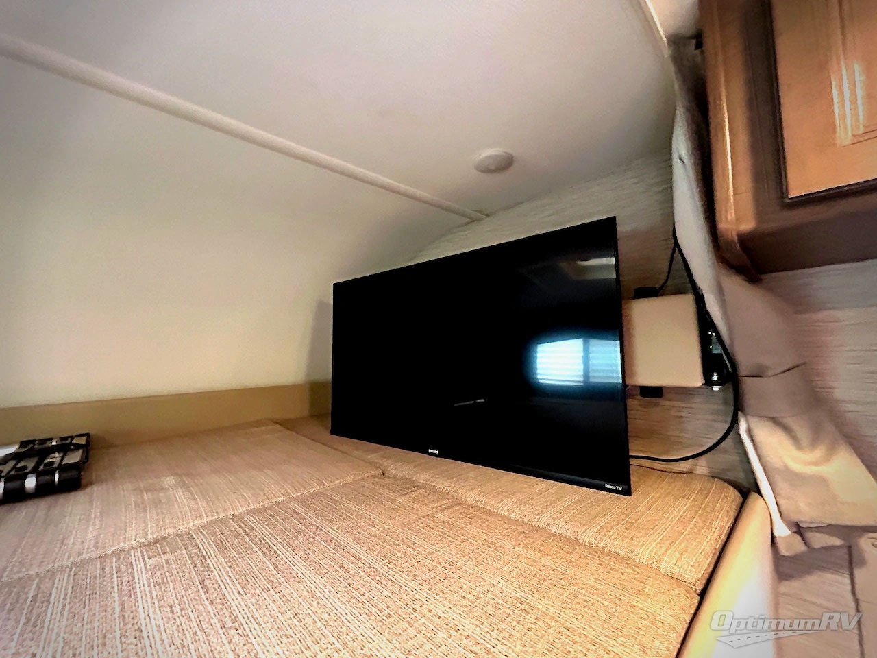 Inside an RV rental: a flat-screen TV is mounted above a comfortable sleeping area with light-colored cushions.. Thor Chateau 2020