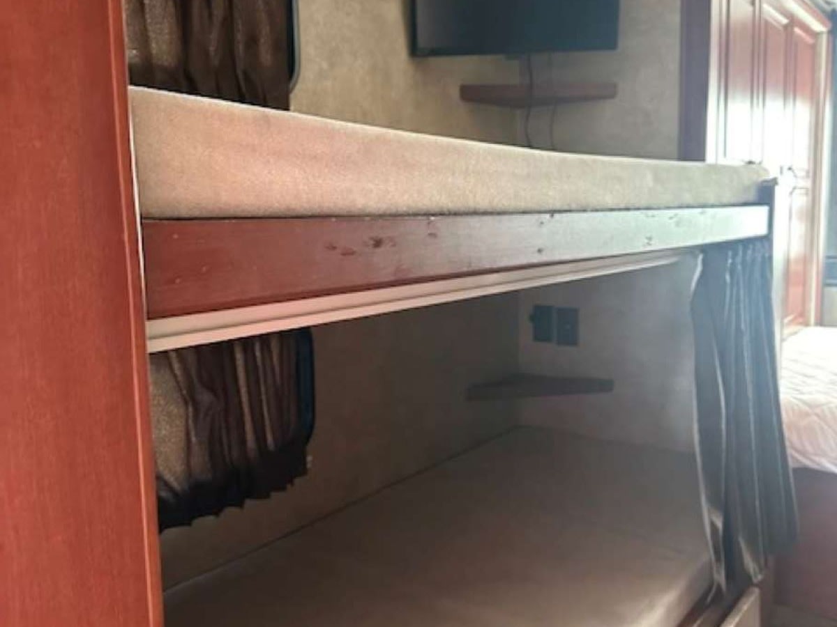 Cozy RV rental bunk beds with privacy curtains and a shelf, providing comfortable sleeping arrangements for family trips.. Winnebago Minnie Winnie 2015