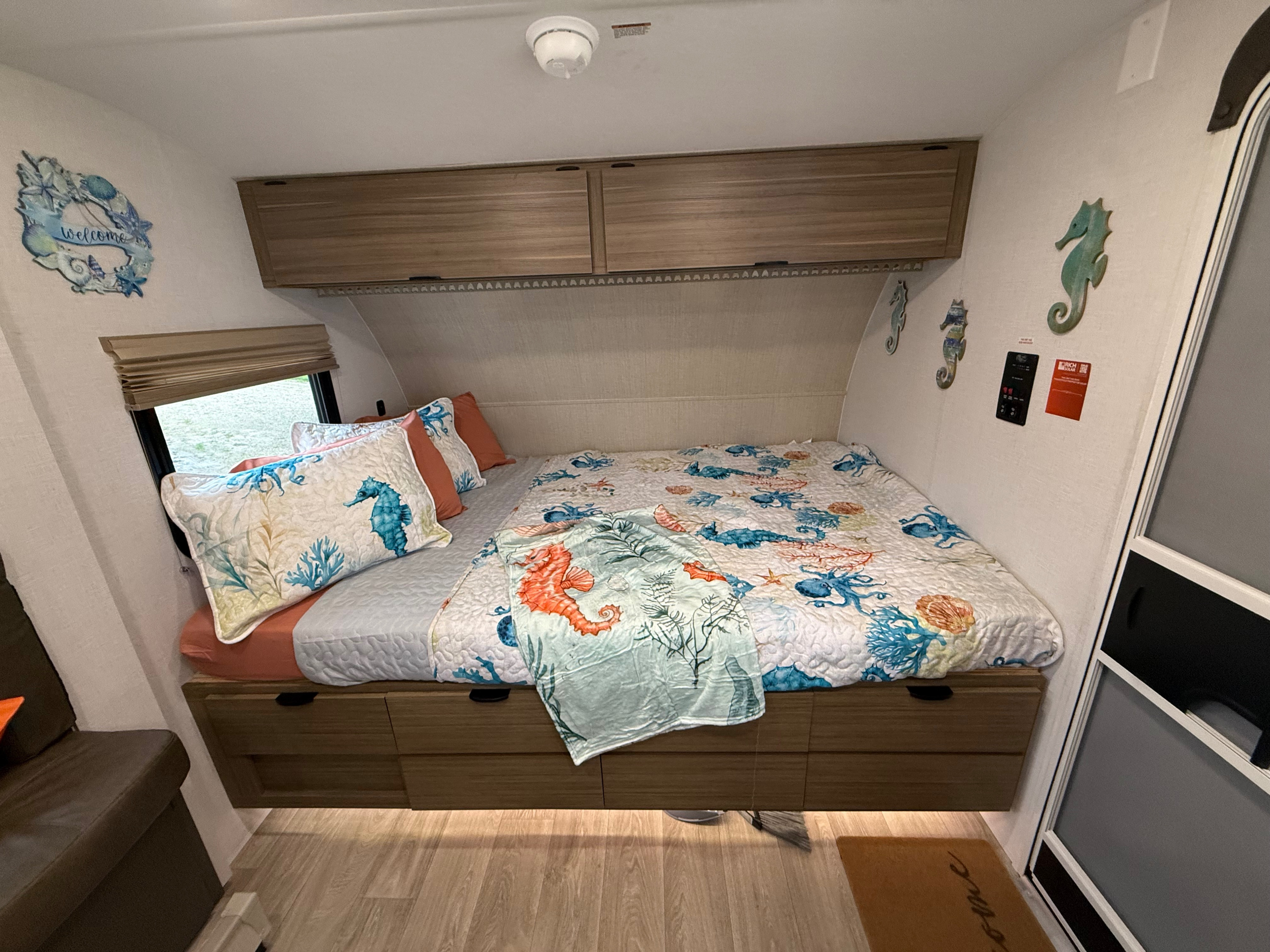 Cozy ocean-themed RV rental bedroom with a bed, under-bed drawers, overhead cabinets, and nautical decor.. Forest River Salem 2026