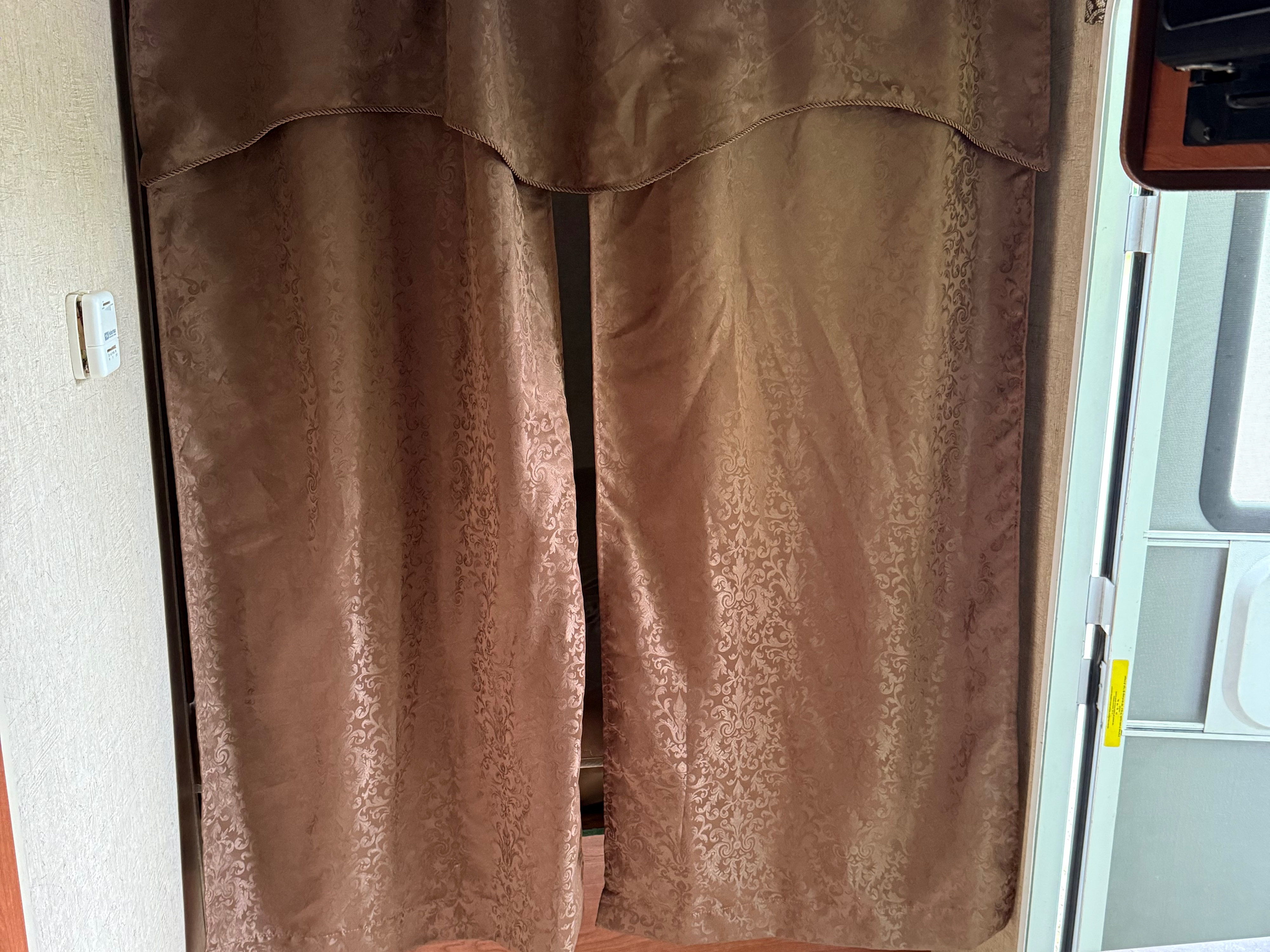 RV rental: Decorative brown patterned curtains with a valance cover a doorway, with an electrical outlet on the left wall.. Sportsmen Classic 2013