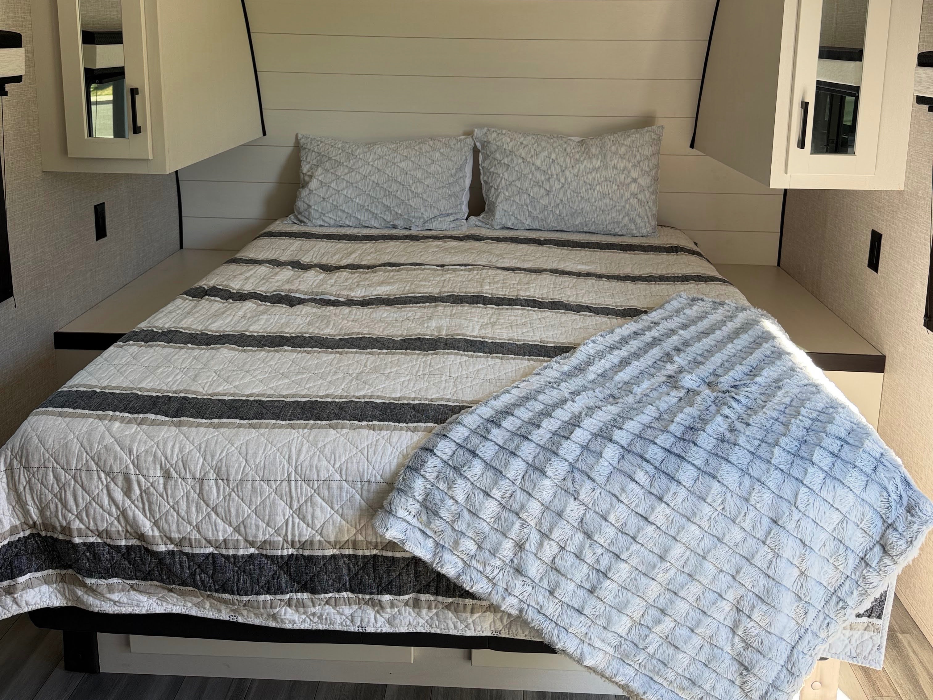 Comfortable RV rental bedroom featuring a striped bed, plush throw blanket, and mirrored storage cabinets.. Jayco Jay Flight 2024