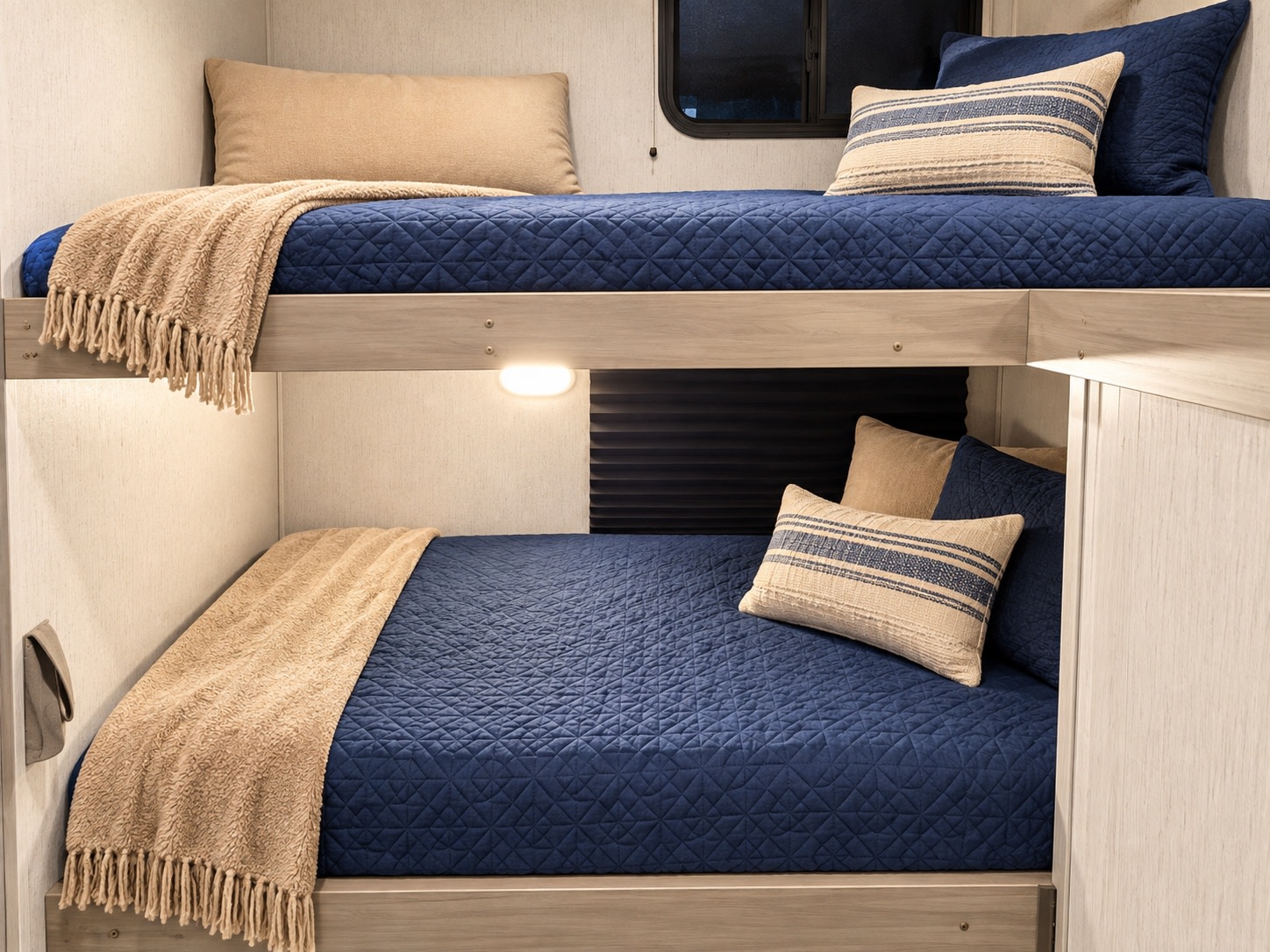 Cozy bunk beds inside a modern RV rental, featuring quilted navy bedding and soft throws for comfortable travel.. Dutchmen Coleman Lantern 2023