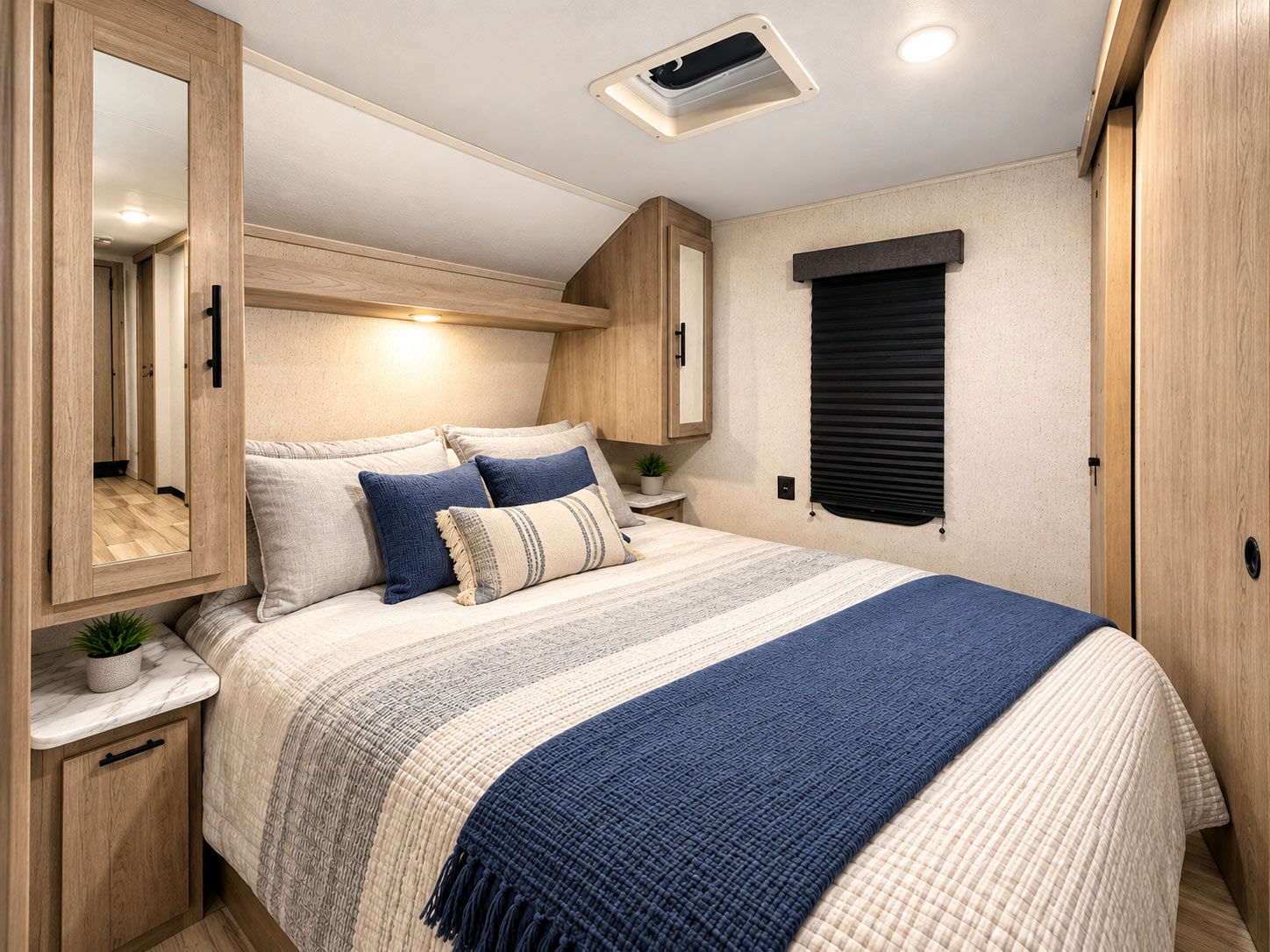 Modern RV rental bedroom with a cozy bed, blue accents, natural wood cabinets, and soft lighting. Your comfortable journey starts here.. Dutchmen Coleman Lantern 2023