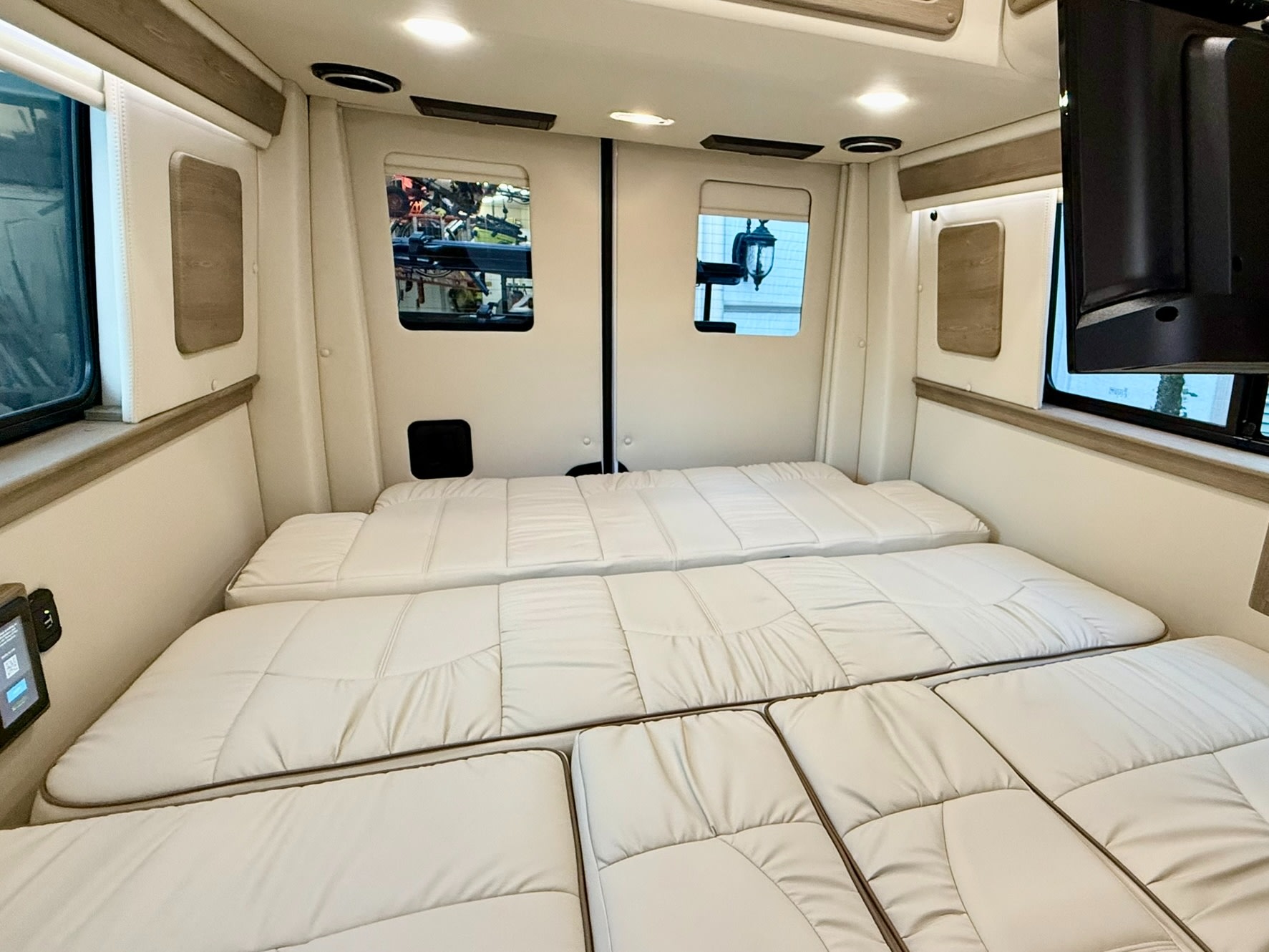 RV rental's comfortable interior features a flexible bed/lounge with soft white cushions, bright lighting, and rear windows.. Midwest Automotive Designs Midwest Automotive Designs Class B 2023