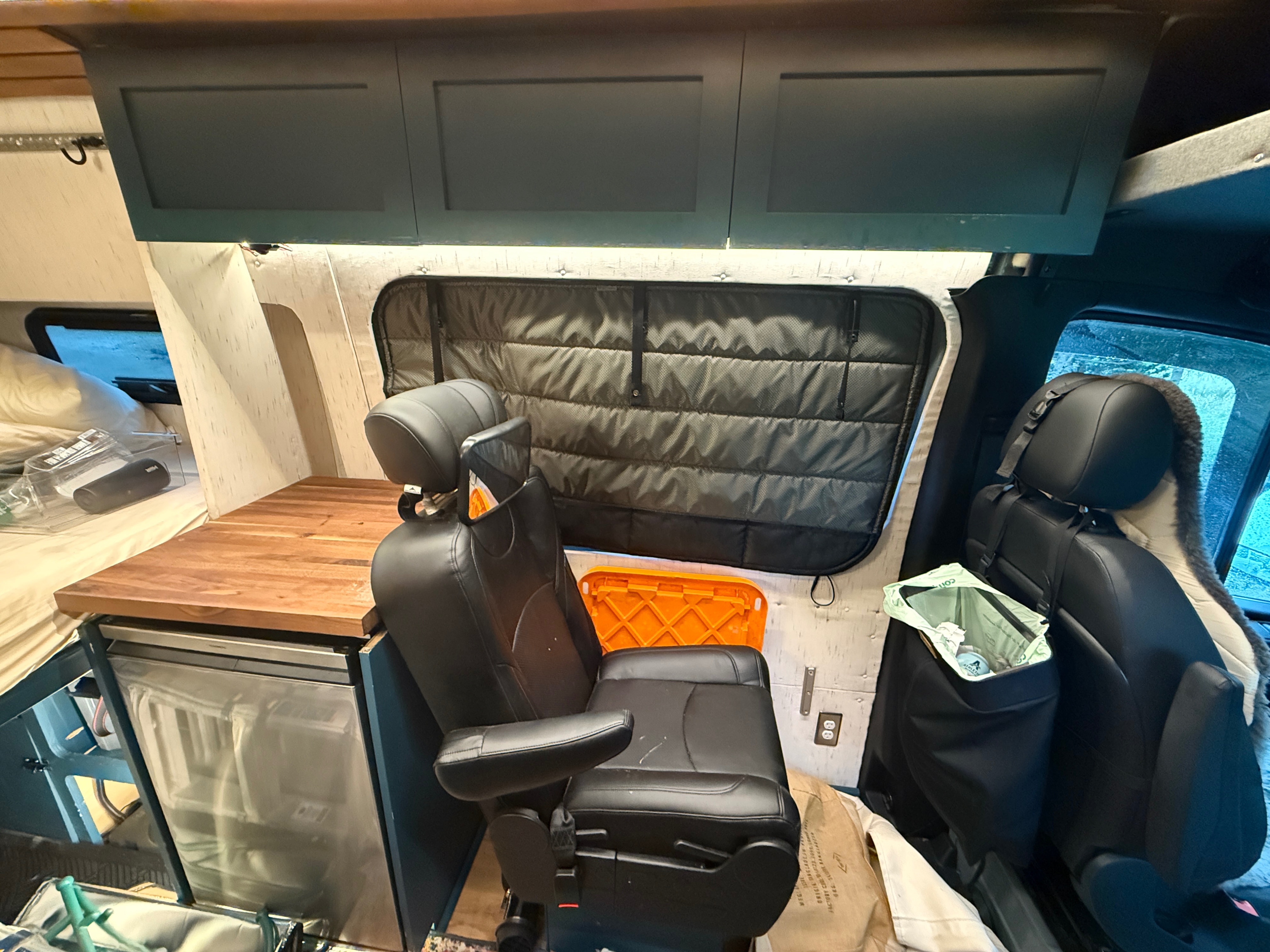 RV rental interior: Camper van with kitchen, bed, swiveling seats, and overhead storage for comfortable mobile living.. Mercedes-Benz Sprinter 2023