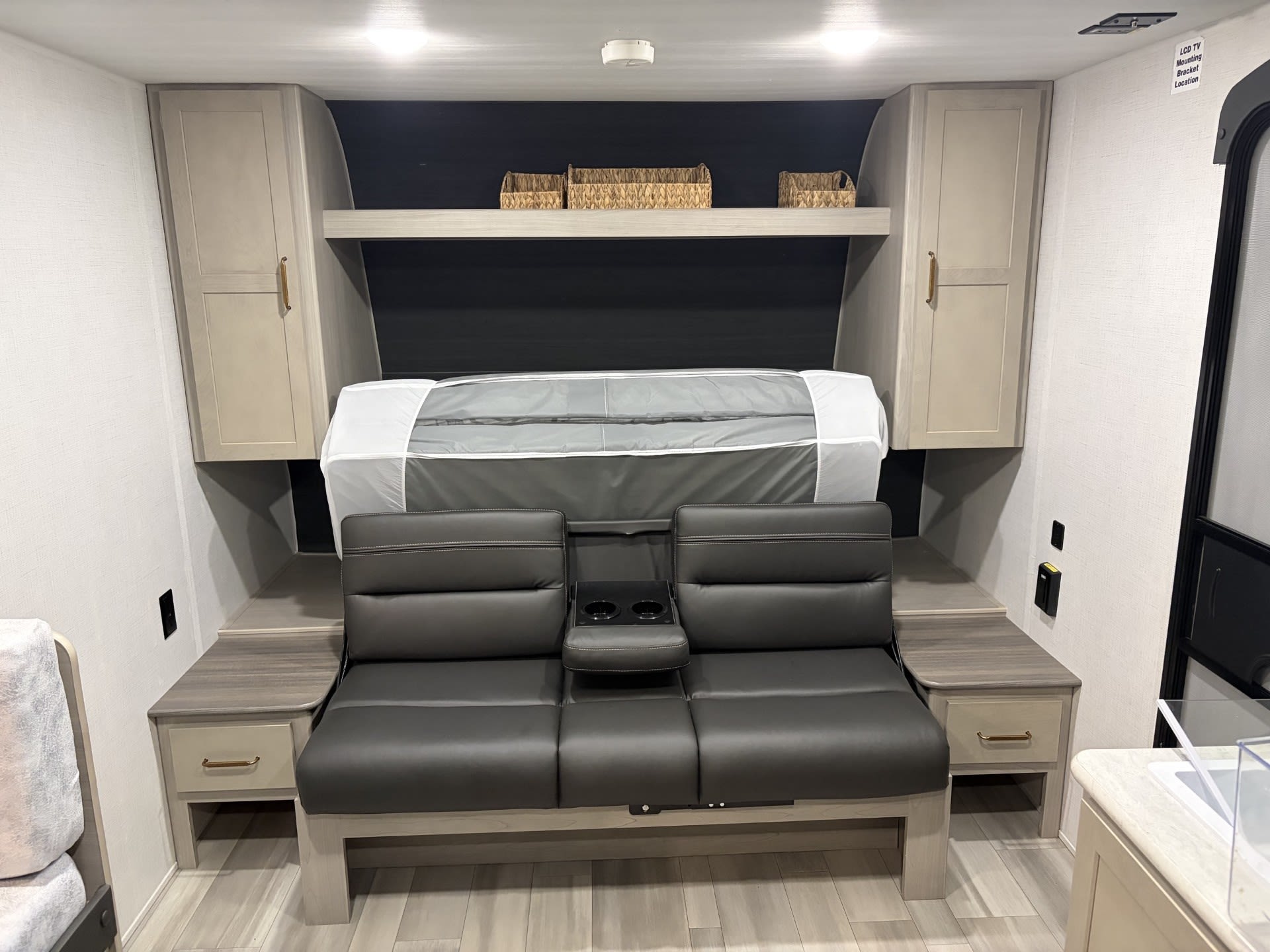 Cozy RV rental interior with a versatile sofa that converts to a bed, overhead storage, and bedside tables.. Keystone RV Springdale 2024