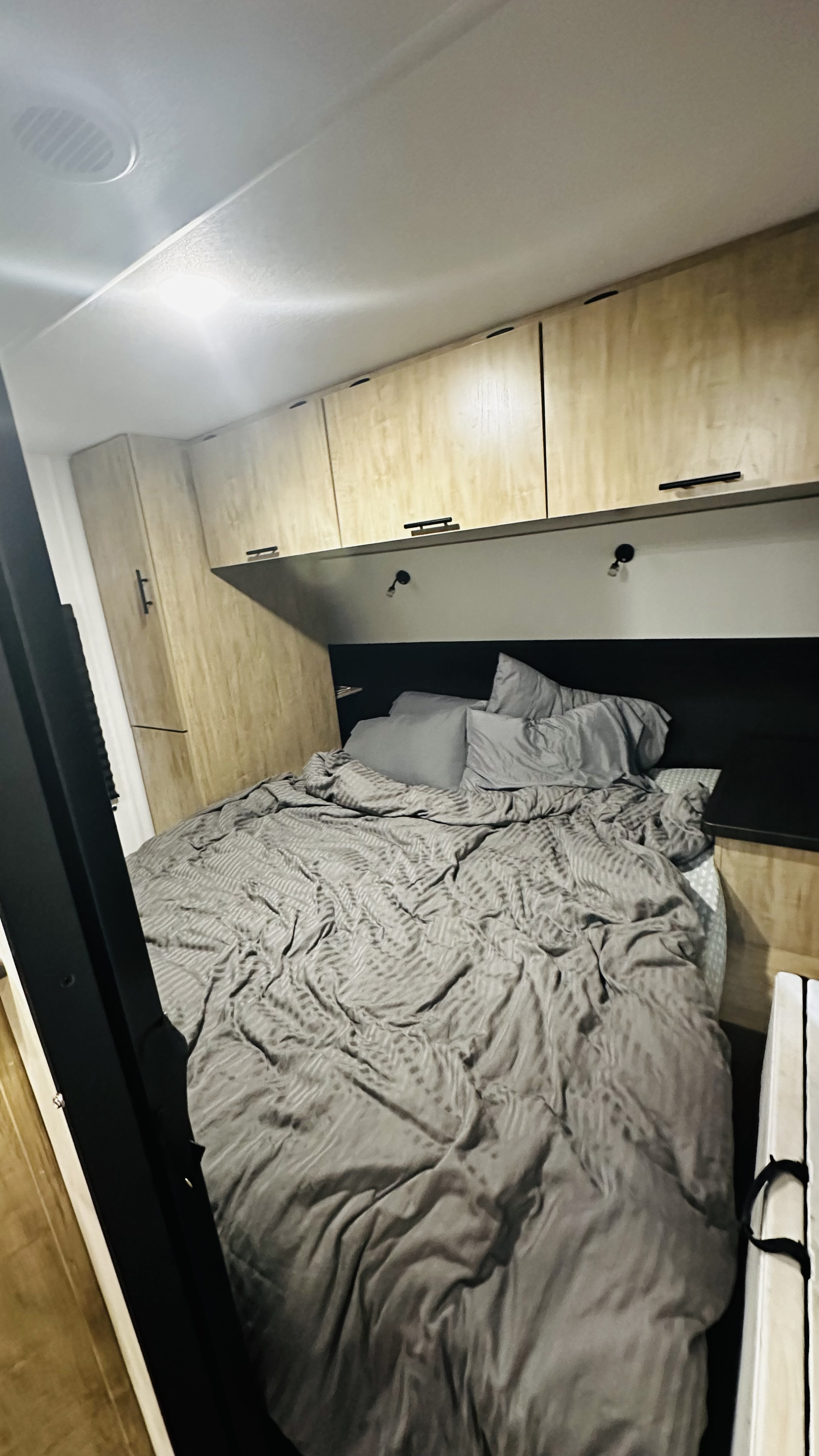 Cozy RV rental bedroom with light wood cabinets, grey bed, and reading lights, perfect for your next trip.. Forest River Cherokee Grey Wolf 2027