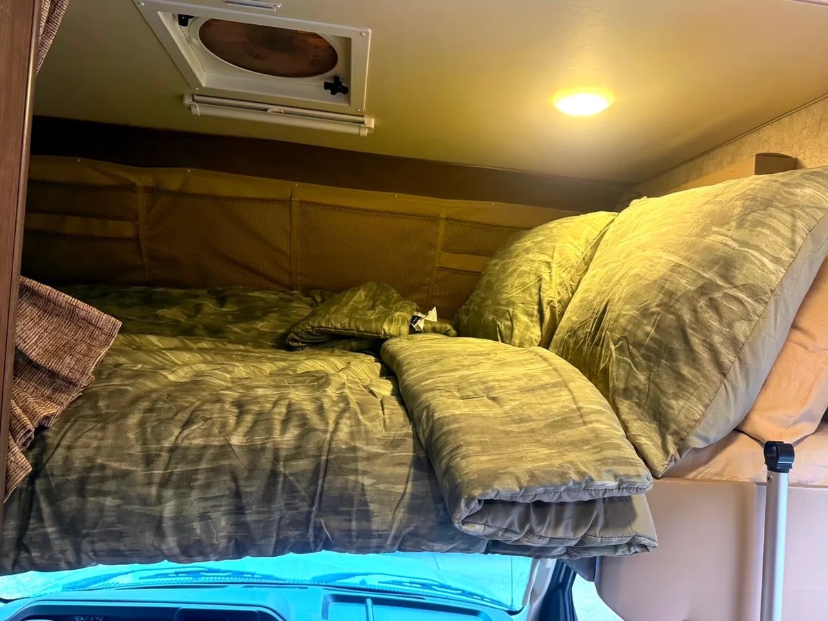 Comfortable RV rental bunk bed with olive bedding, roof vent, and storage for a cozy night's sleep on your adventure.. Adventurer Adventurer Motorhome 2017