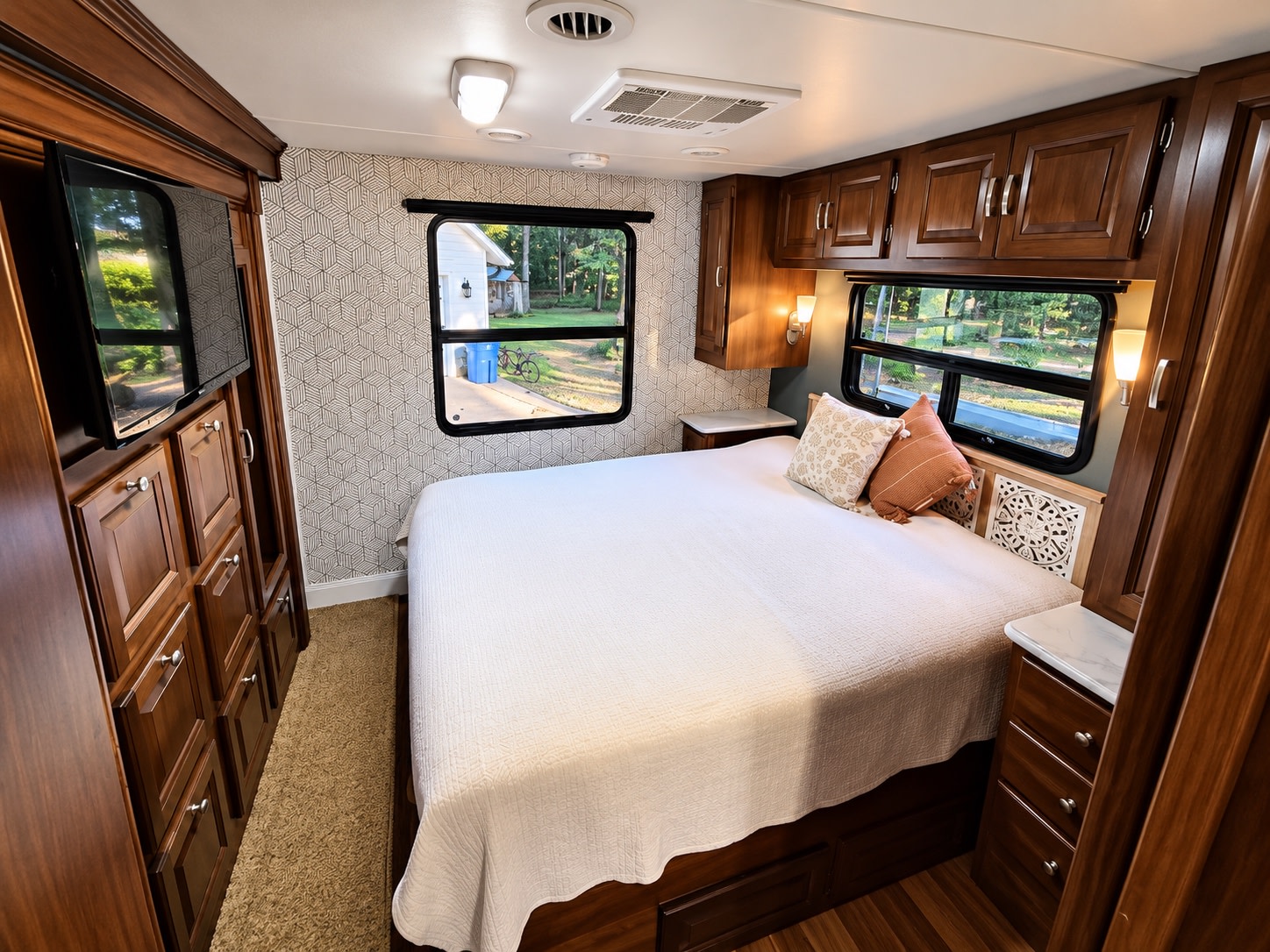Spacious RV rental bedroom with dark wood cabinets, a wall-mounted TV, comfy bed, and lovely outdoor views from windows.. Georgetown Georgetown Motorhome 2014