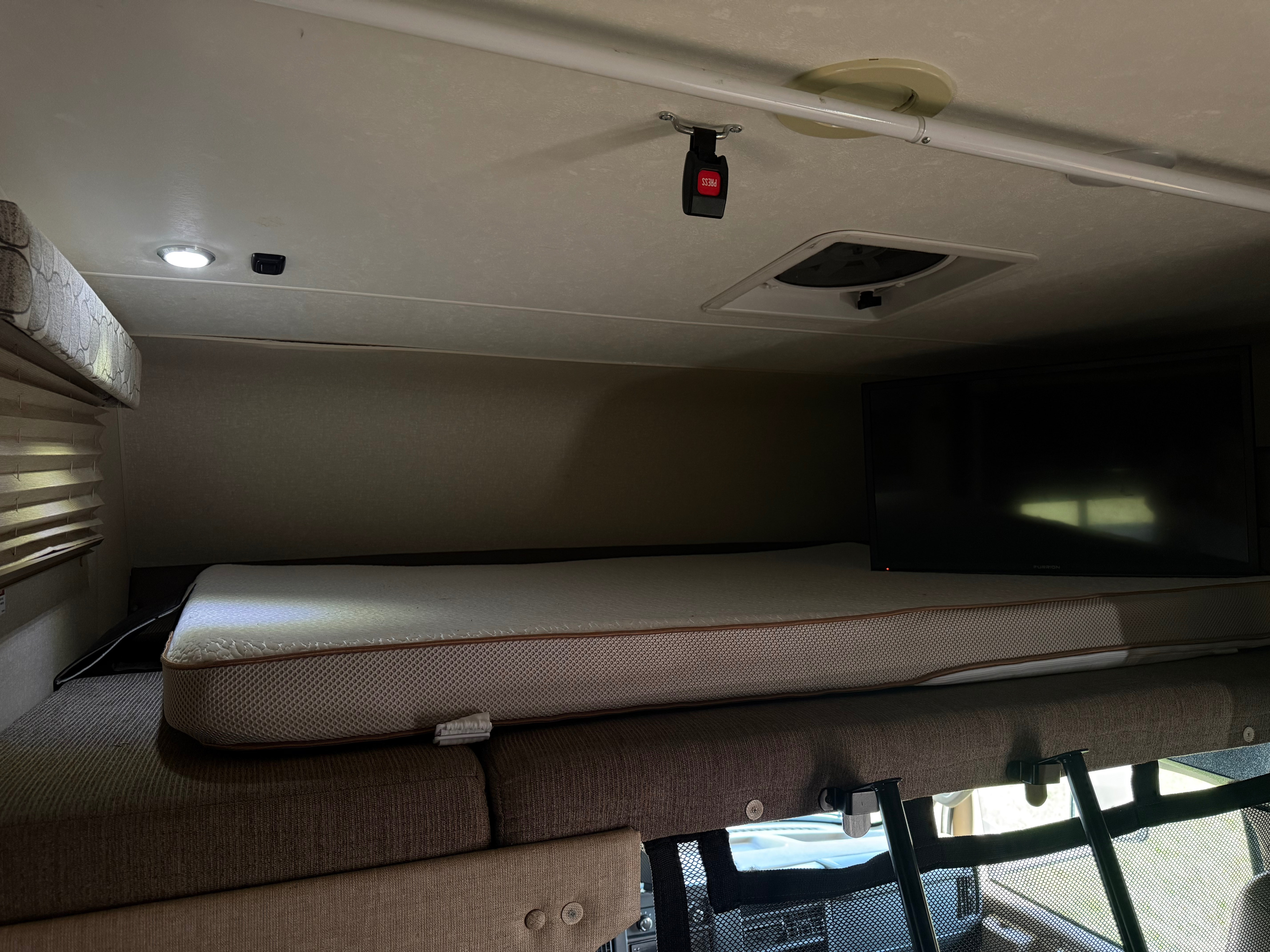 RV rental cab-over bunk with mattress, TV, overhead lights, a safety rail, and a mesh safety net for comfort and security.. Coachmen Freelander 26DS 2019