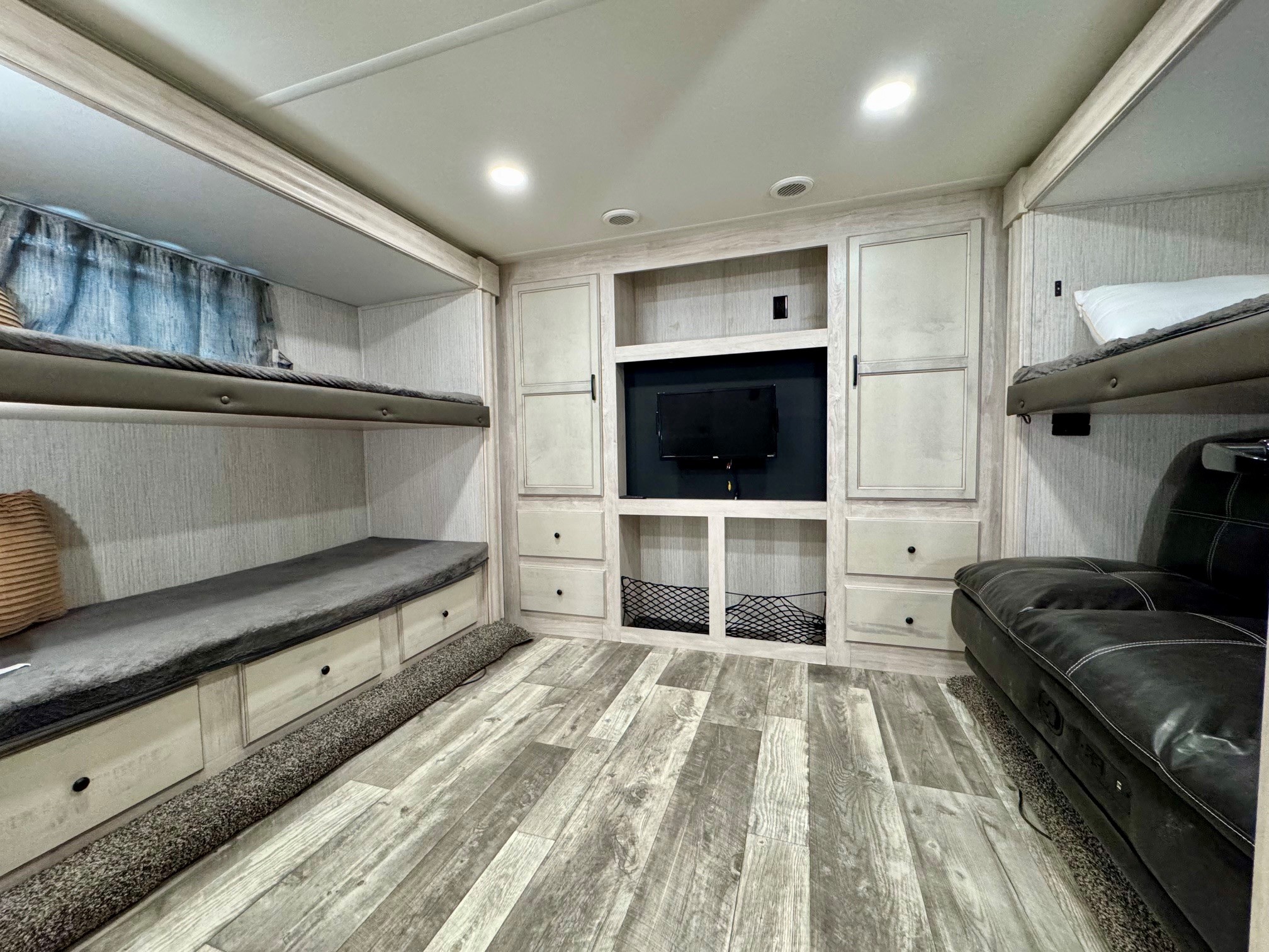 This RV rental bunkhouse features a central entertainment unit, two bunk beds, storage, and a comfy sofa, perfect for families.. Forest River Sandpiper 2022