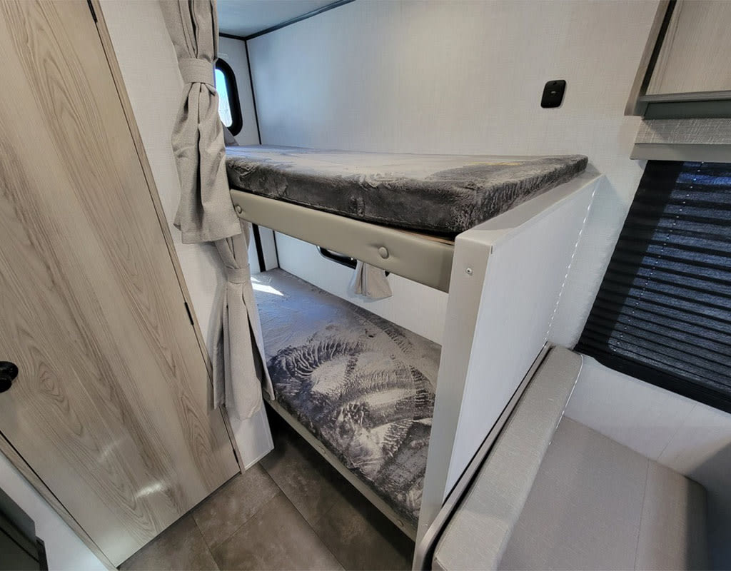 RV rental interior: Compact sleeping area with bunk beds, fresh mattresses, privacy curtains, and window blinds.. Forest River Salem 2025