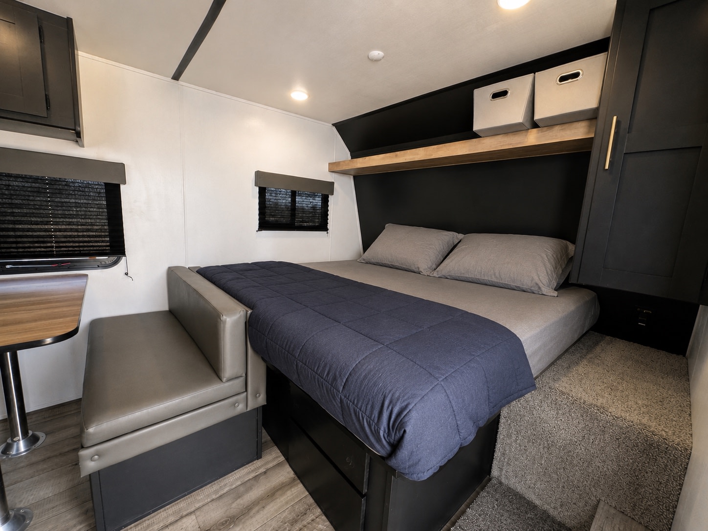 Modern RV rental interior with a cozy bed, built-in bench seating, and storage. Ideal for your next camper adventure.. Keystone RV Springdale 2022