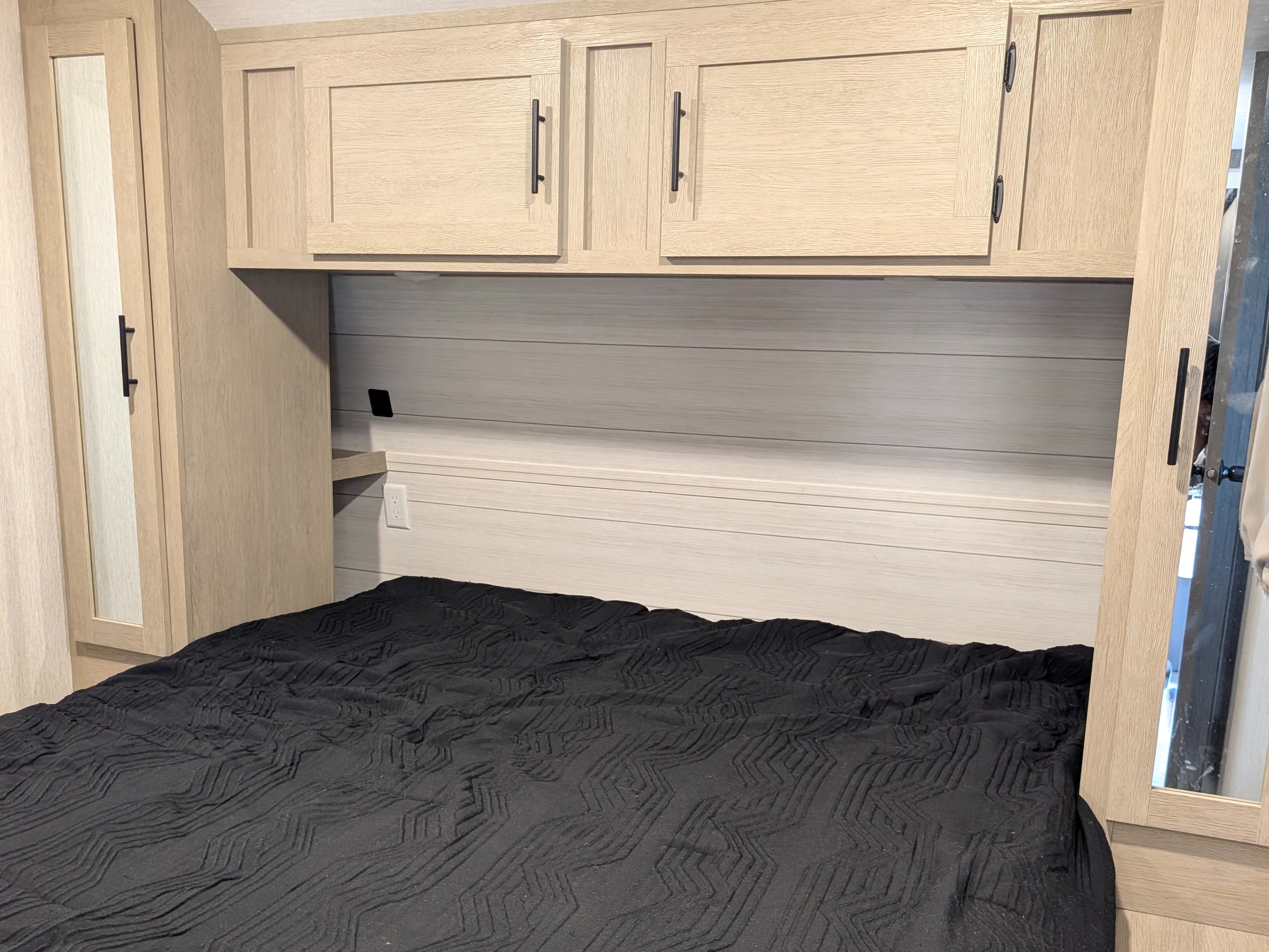 Modern RV rental bedroom with light wood cabinets, a black quilted bed, and convenient storage for your next adventure.. Forest River Salem Cruise Lite Platinum 2024