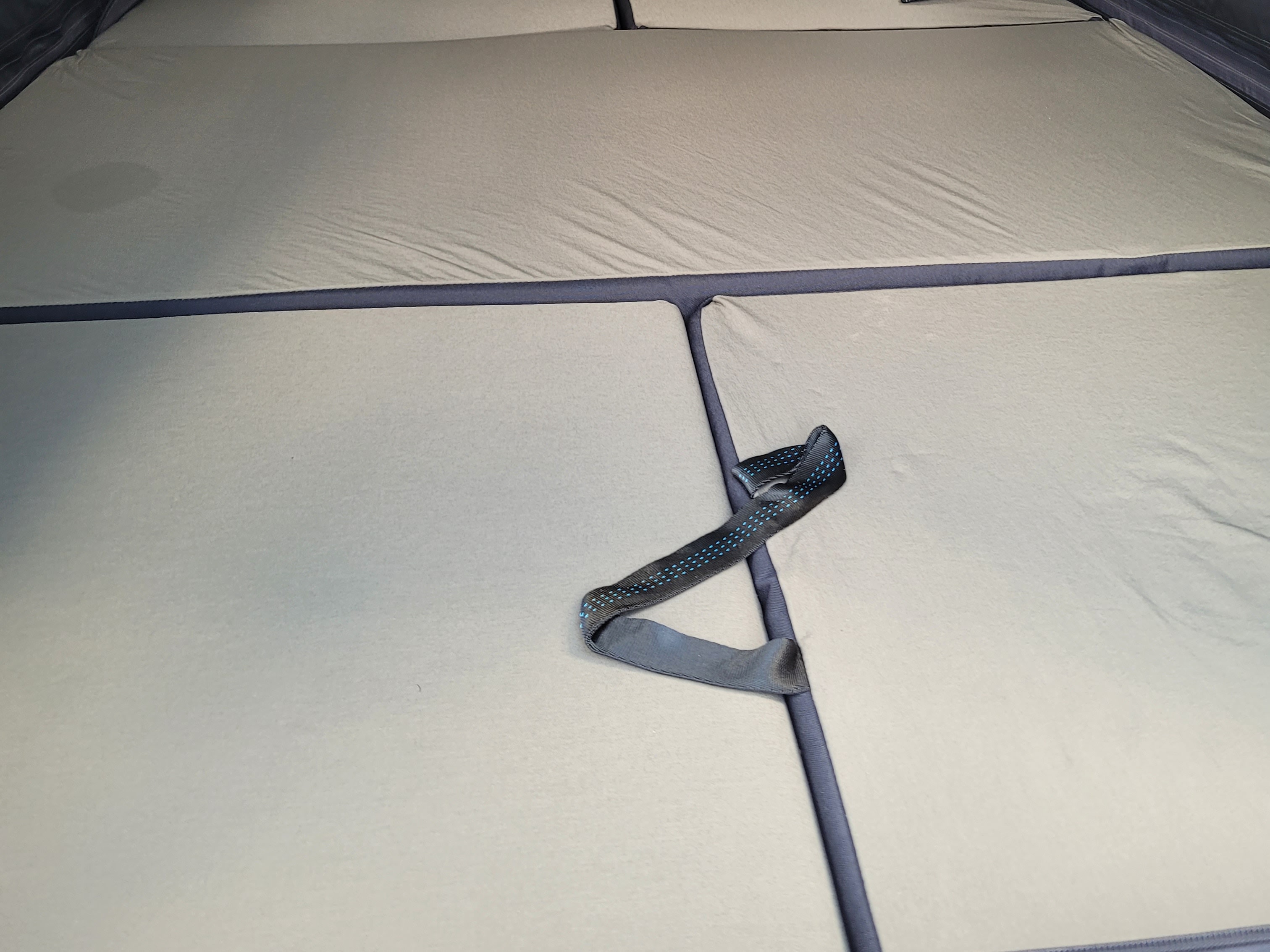 RV rental interior: segmented mattress with securing strap, offering a comfortable sleep setup.. Rivian R1T 2023