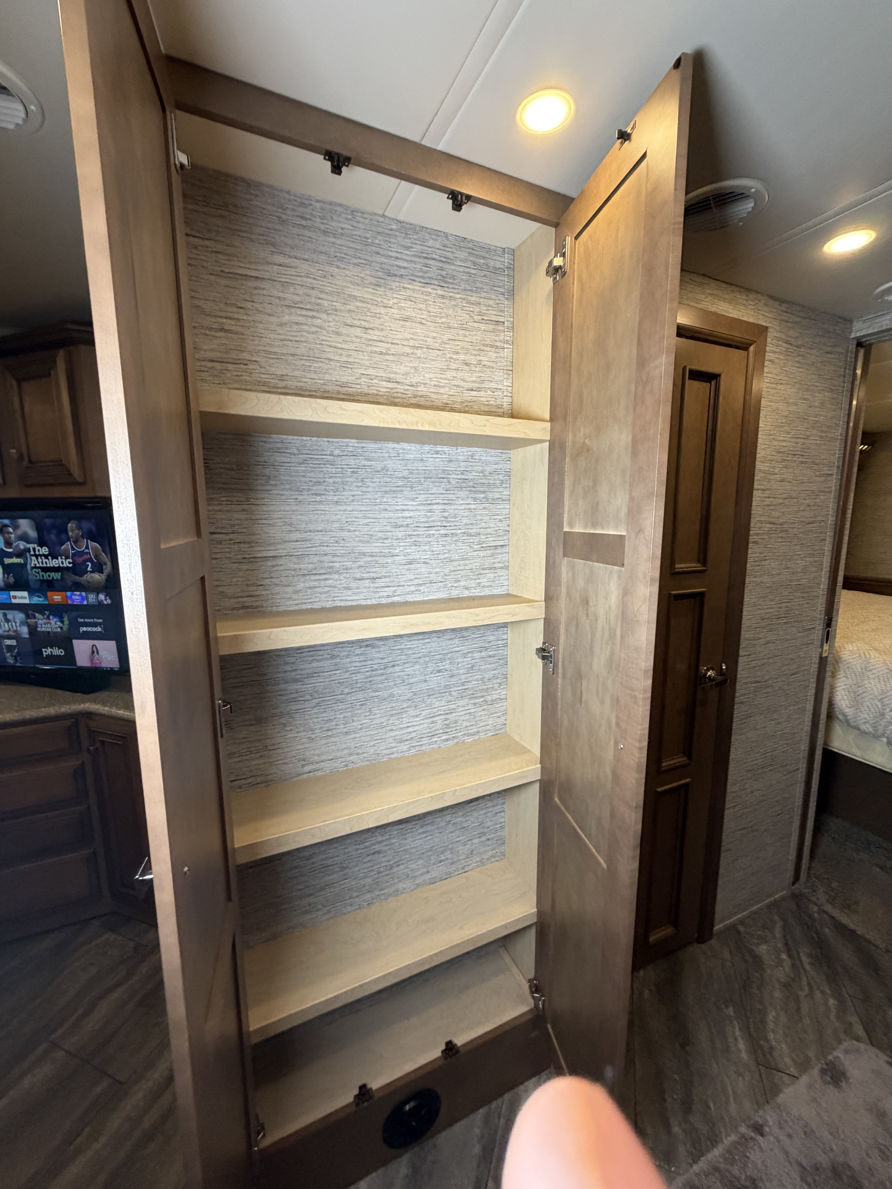 Spacious open closet/pantry in an RV rental, offering ample storage with light wood shelves and textured walls.. Newmar Bay Star 2019