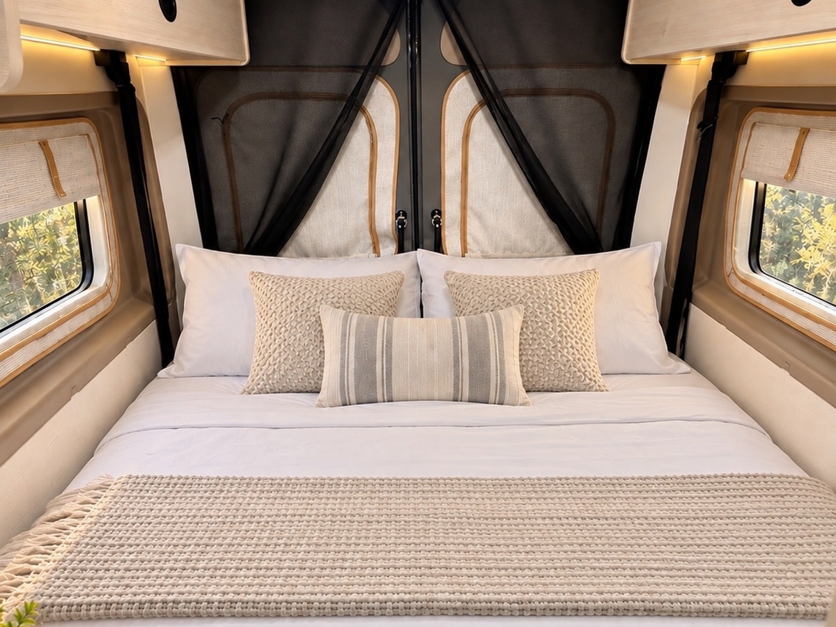 Cozy rv rental interior featuring a comfortable bed with white bedding, textured pillows, and windows with scenic views.. Winnebago Solis 59P 2027