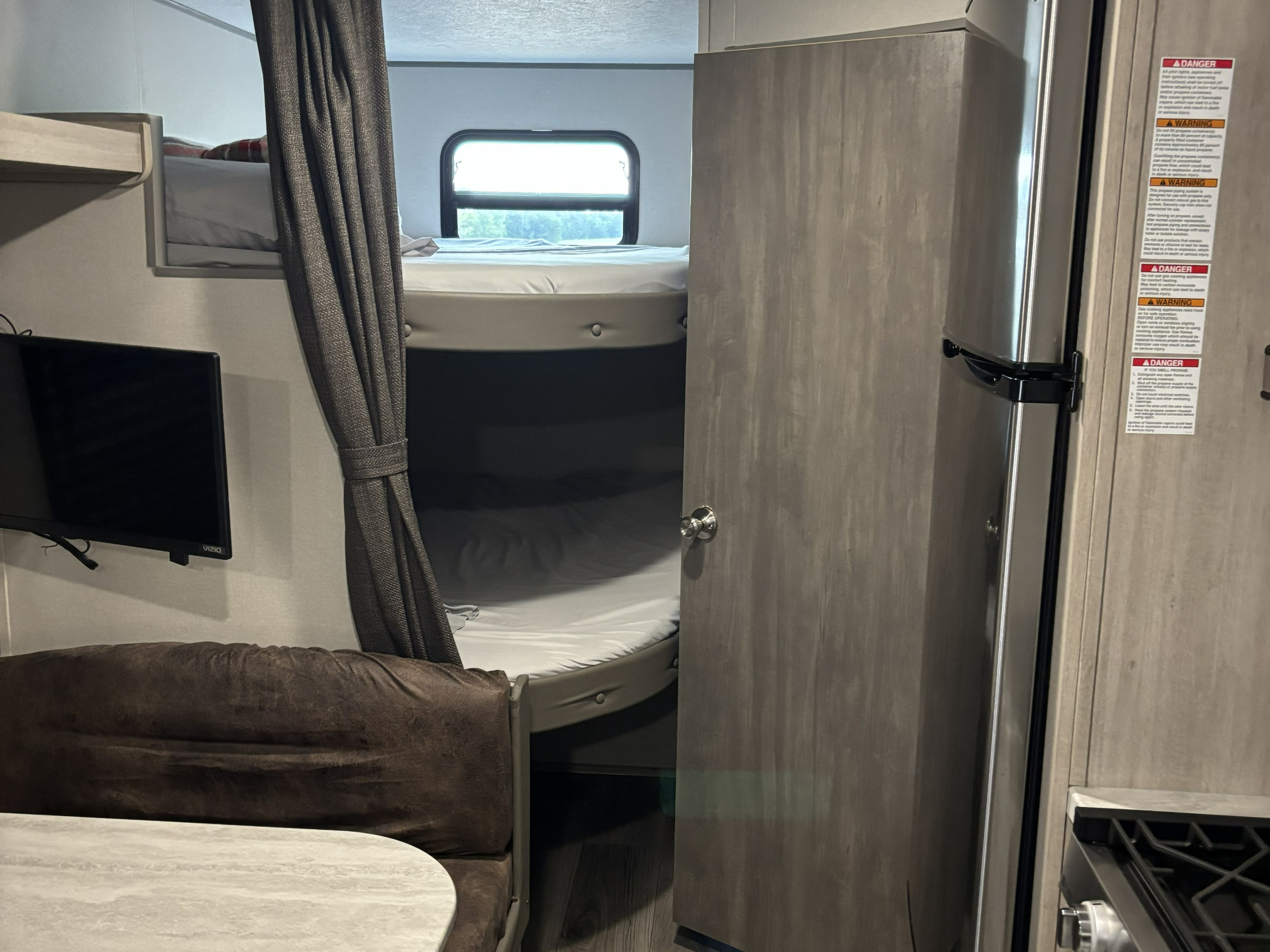RV rental interior: features cozy bunk beds, a dinette, wall-mounted TV, and an efficient kitchenette.. Coachmen 261BH 2024