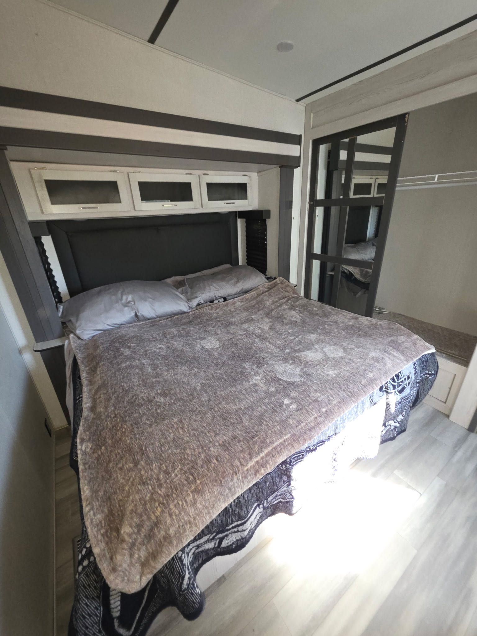 Comfortable and modern RV rental bedroom with a large bed, overhead cabinets, and a sliding closet door. Perfect for a cozy stay.. Keystone RV Sprinter Limited 2021