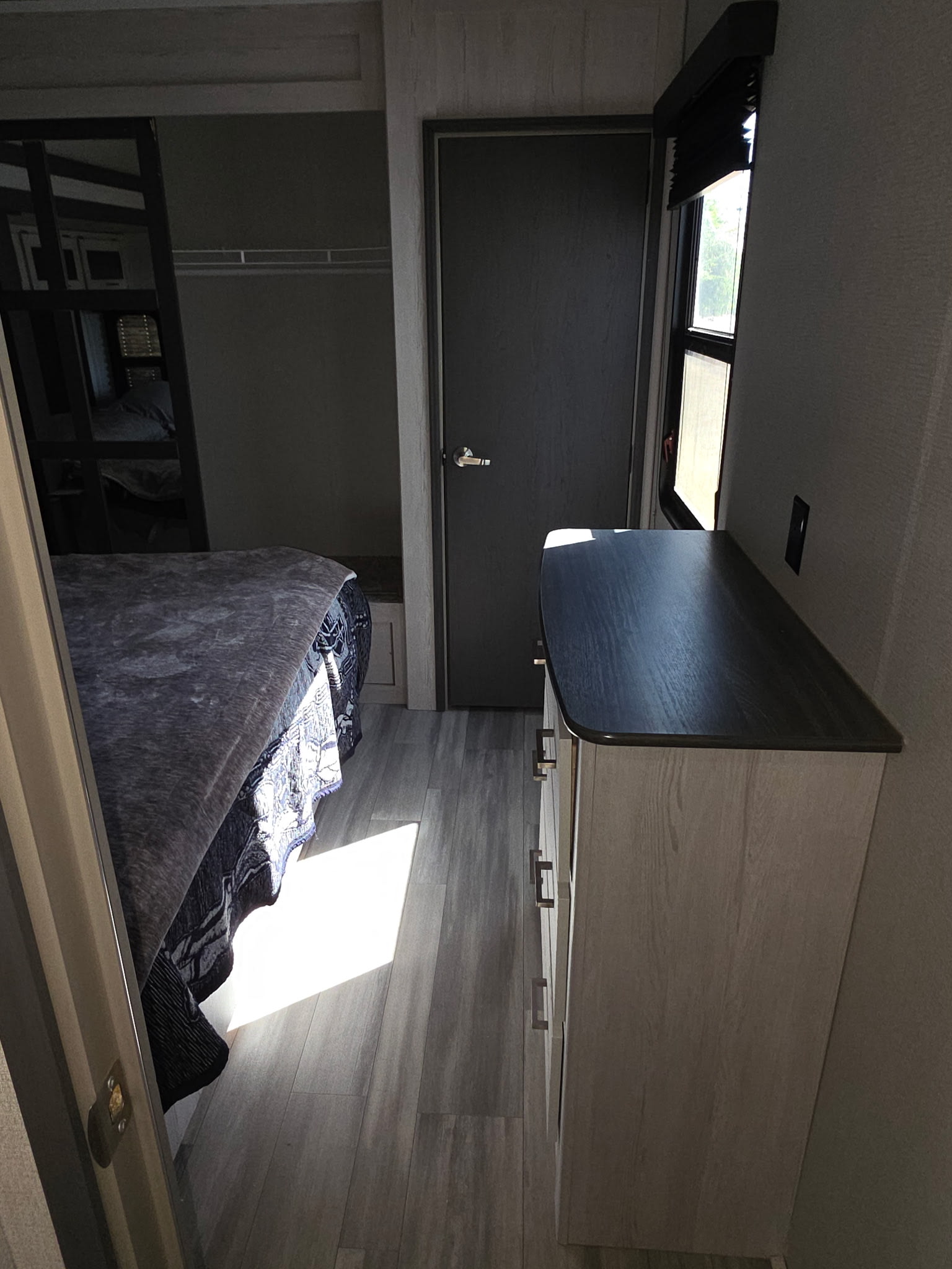 Compact RV rental bedroom with bunk beds, a dresser, and a window letting in bright sunlight on the wood-look floor.. Keystone RV Sprinter Limited 2021