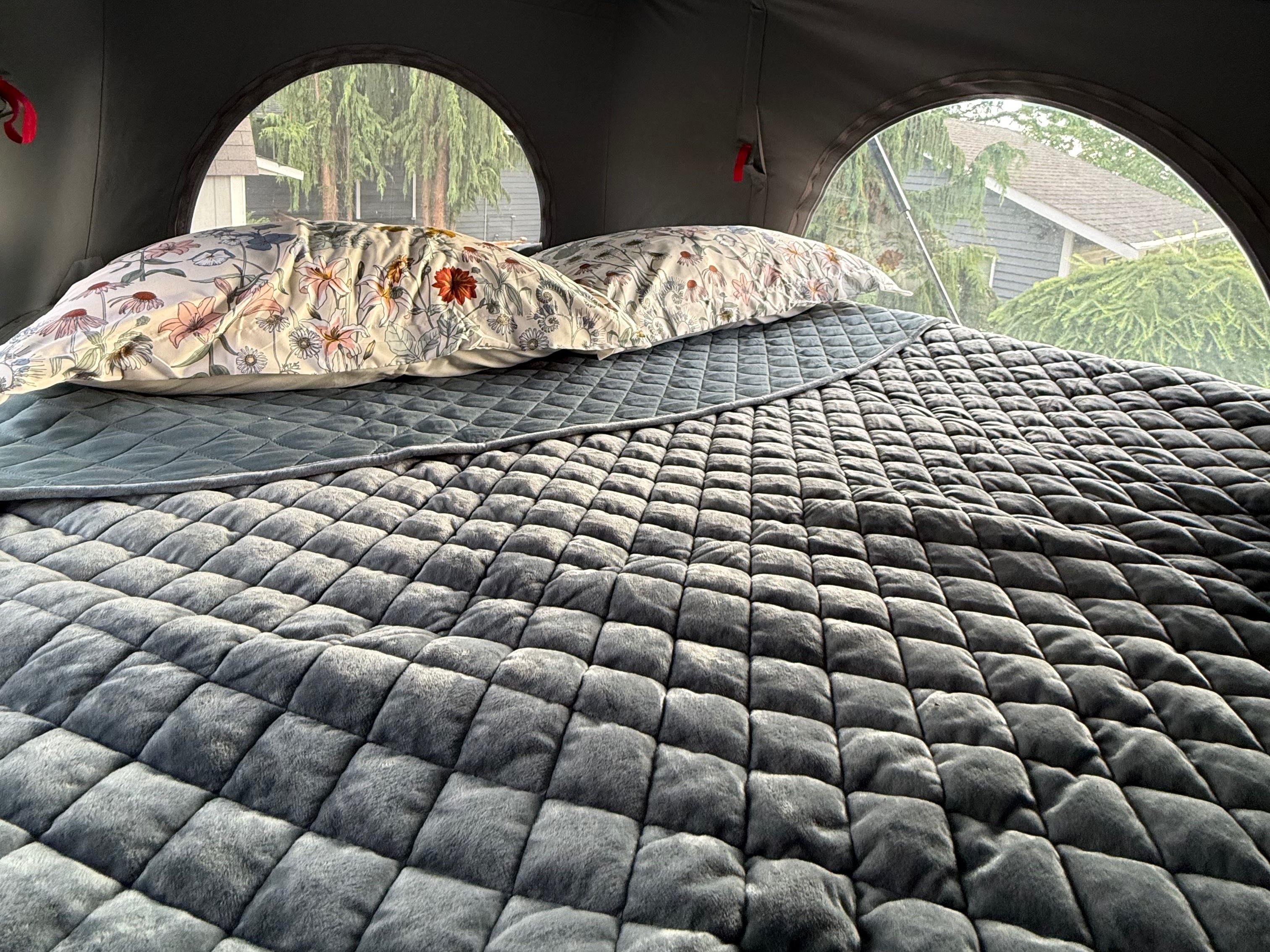 Cozy RV rental bed with floral pillows & a soft, quilted blanket, offering comfort for your journey.. Winnebago Solis 2023