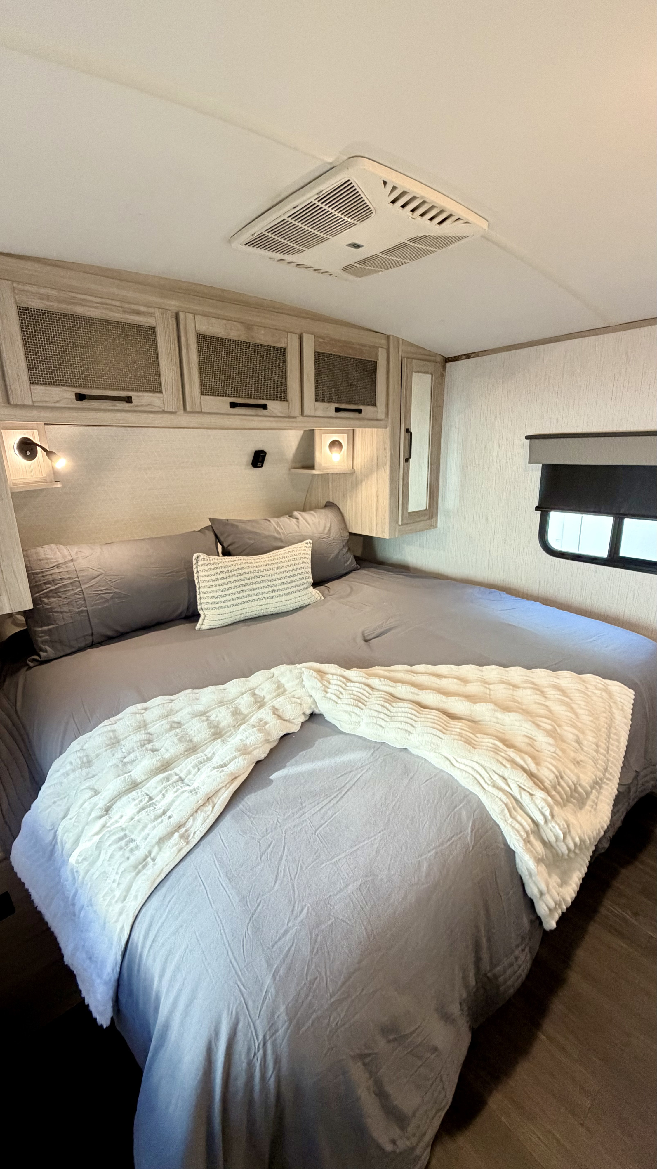A comfortable RV rental bedroom with gray bedding, a white throw, and built-in storage. Ideal for your travels.. Heartland RVs Other 2022