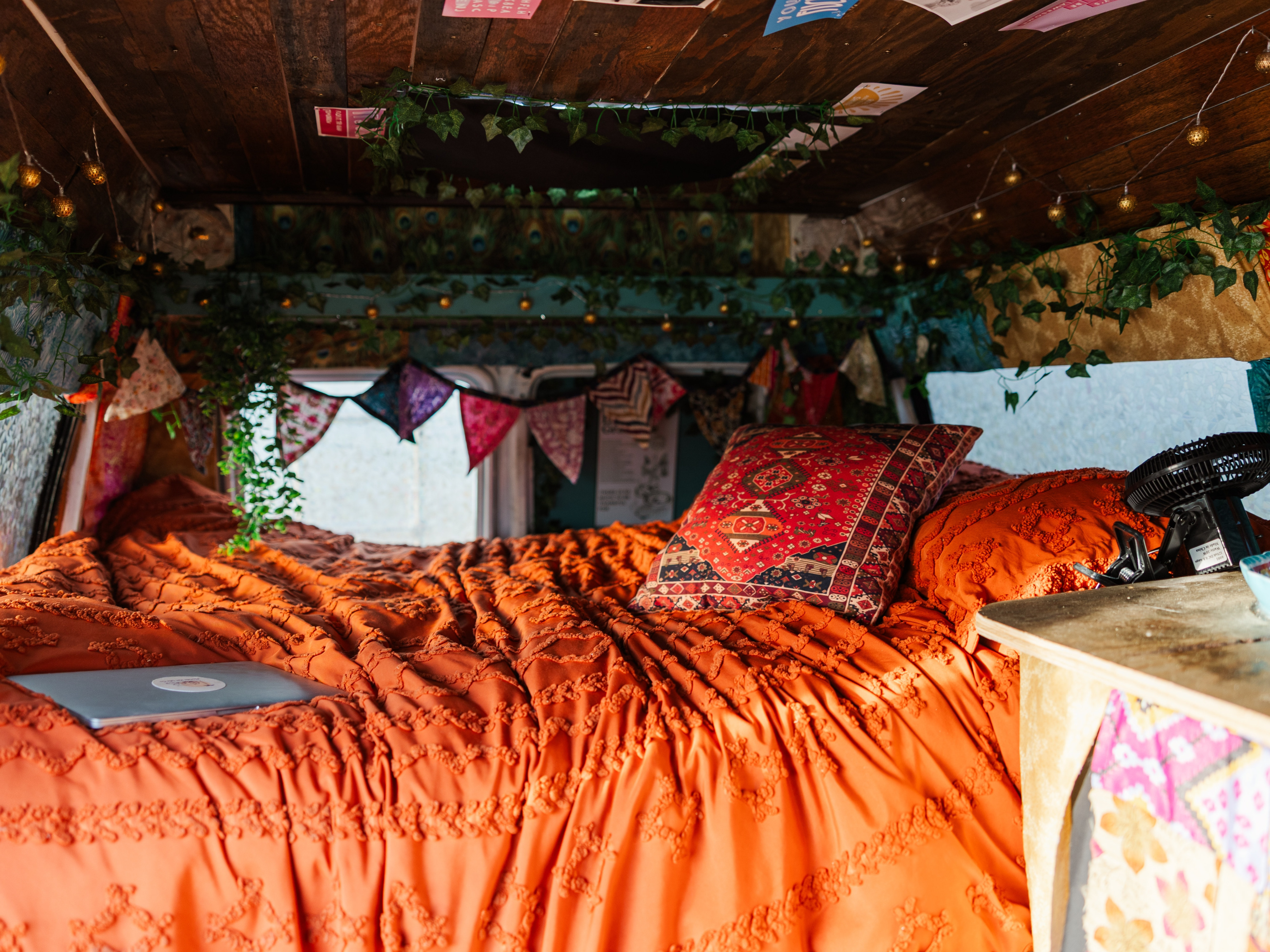 RV rental: Cozy, bohemian van interior with textured orange bed, decorative pillow, string lights, and a laptop.. Dodge Ram 1500 2000