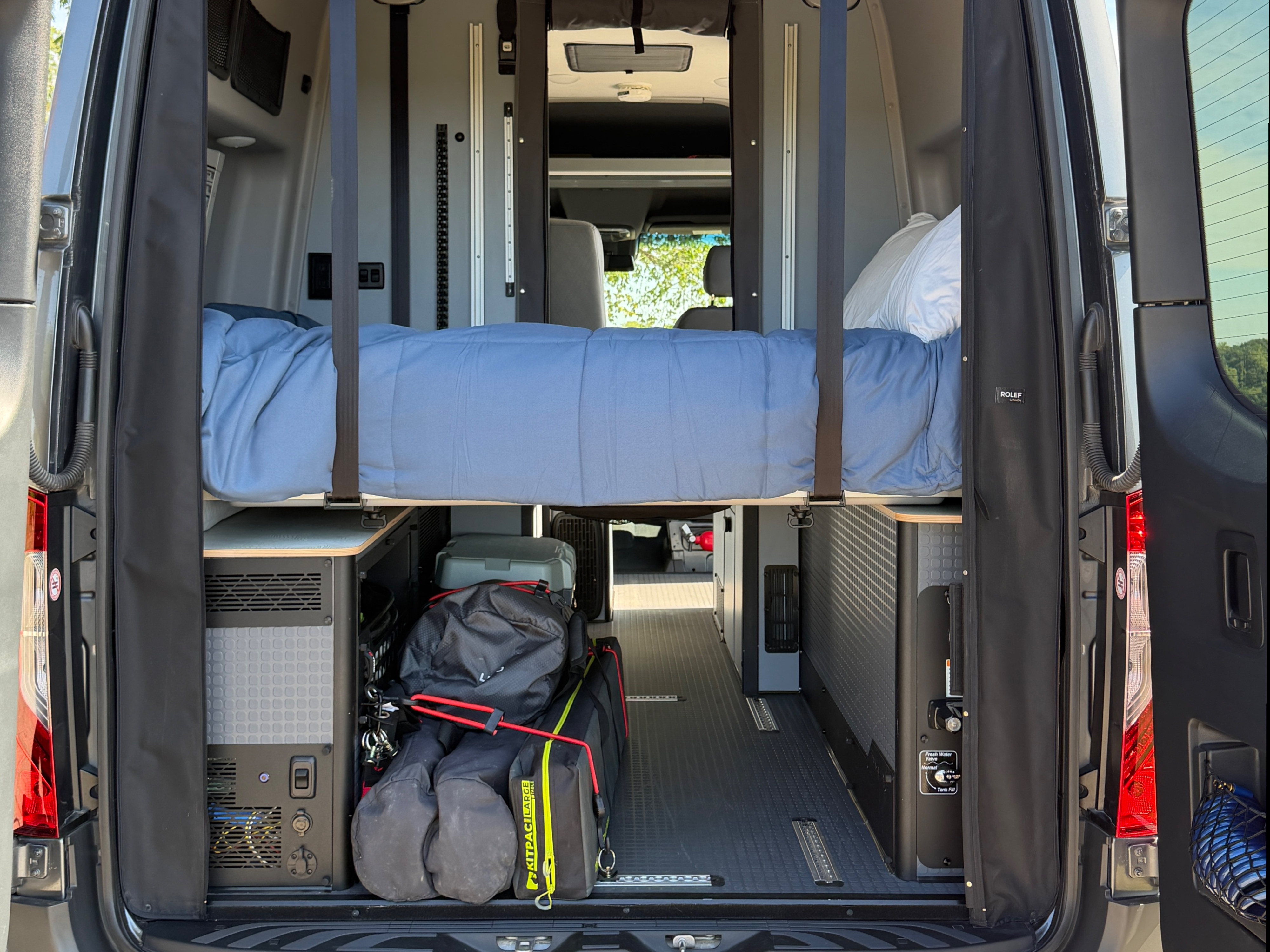 Inside a spacious RV rental camper van with an elevated bed, ample storage, and camping gear, ready for adventure.. Winnebago Revel 2025
