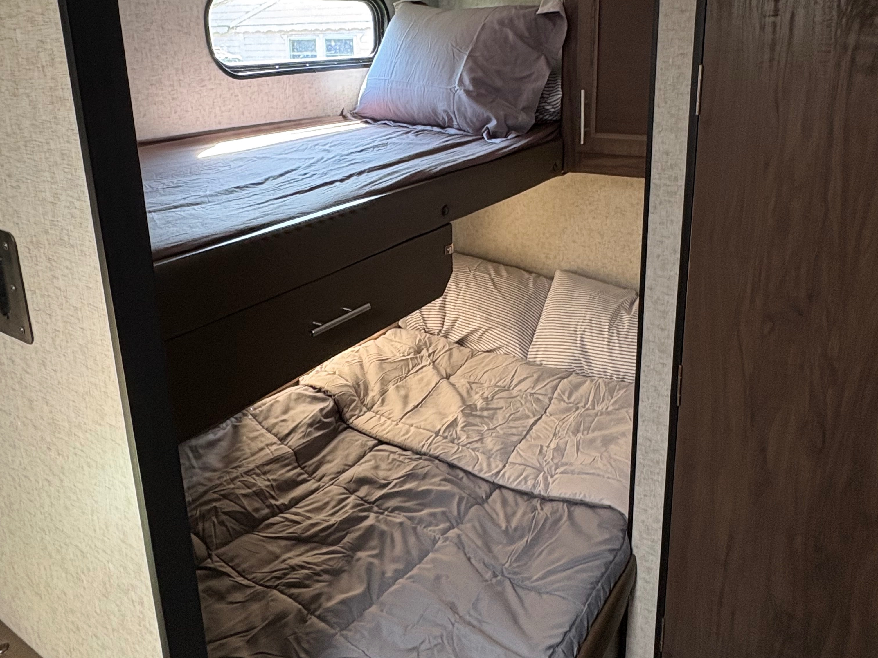 RV rental: Comfortable bunk beds with bedding. The top bunk has a window; the lower bunk features striped pillows.. Forest River Cherokee Grey Wolf 2018