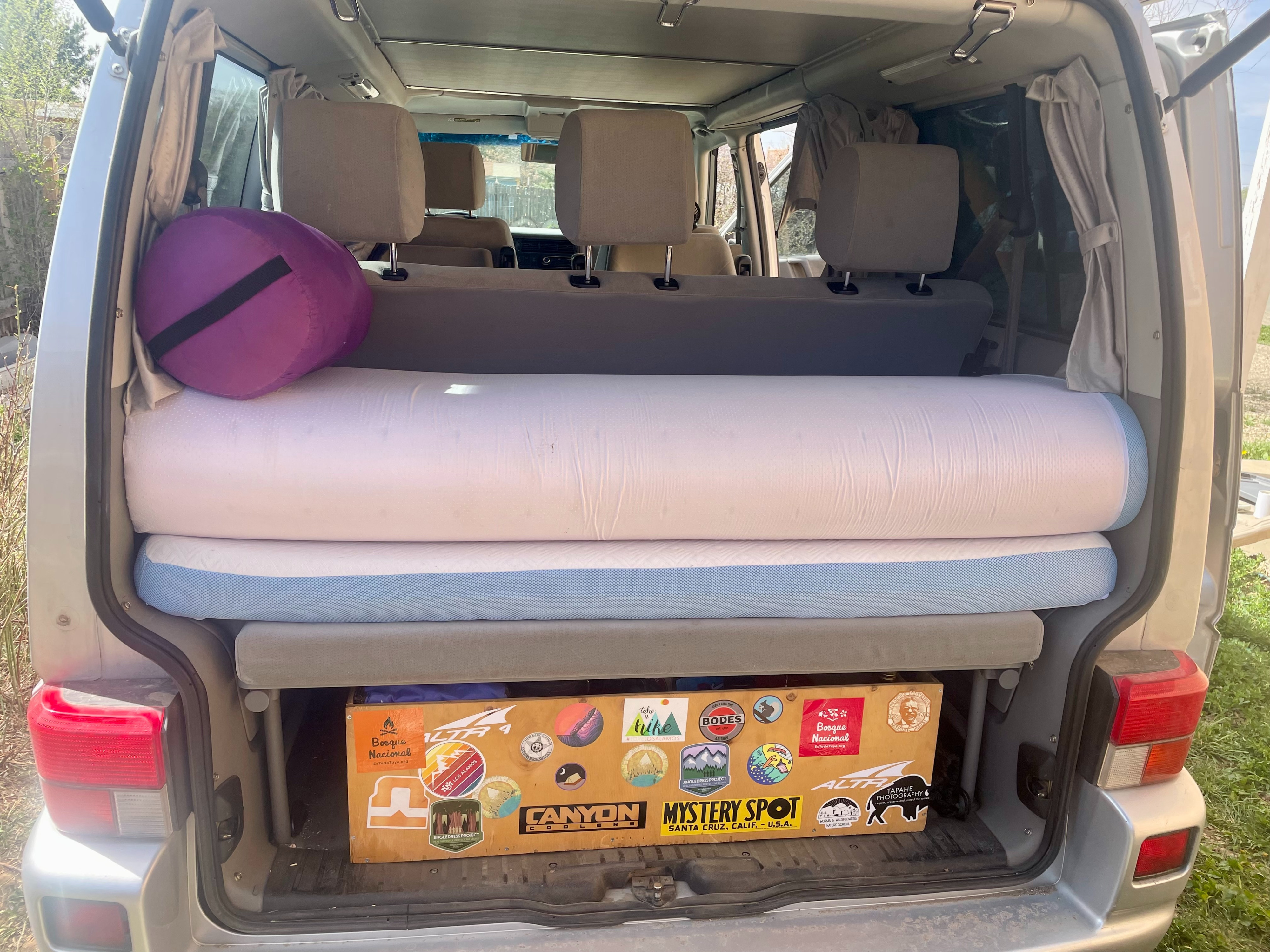 RV rental ready for adventure! Inside this camper van, find rolled mattresses, a pillow, & sticker-covered storage box.. Eurovan Camper Eurovan Camper Class B 2002