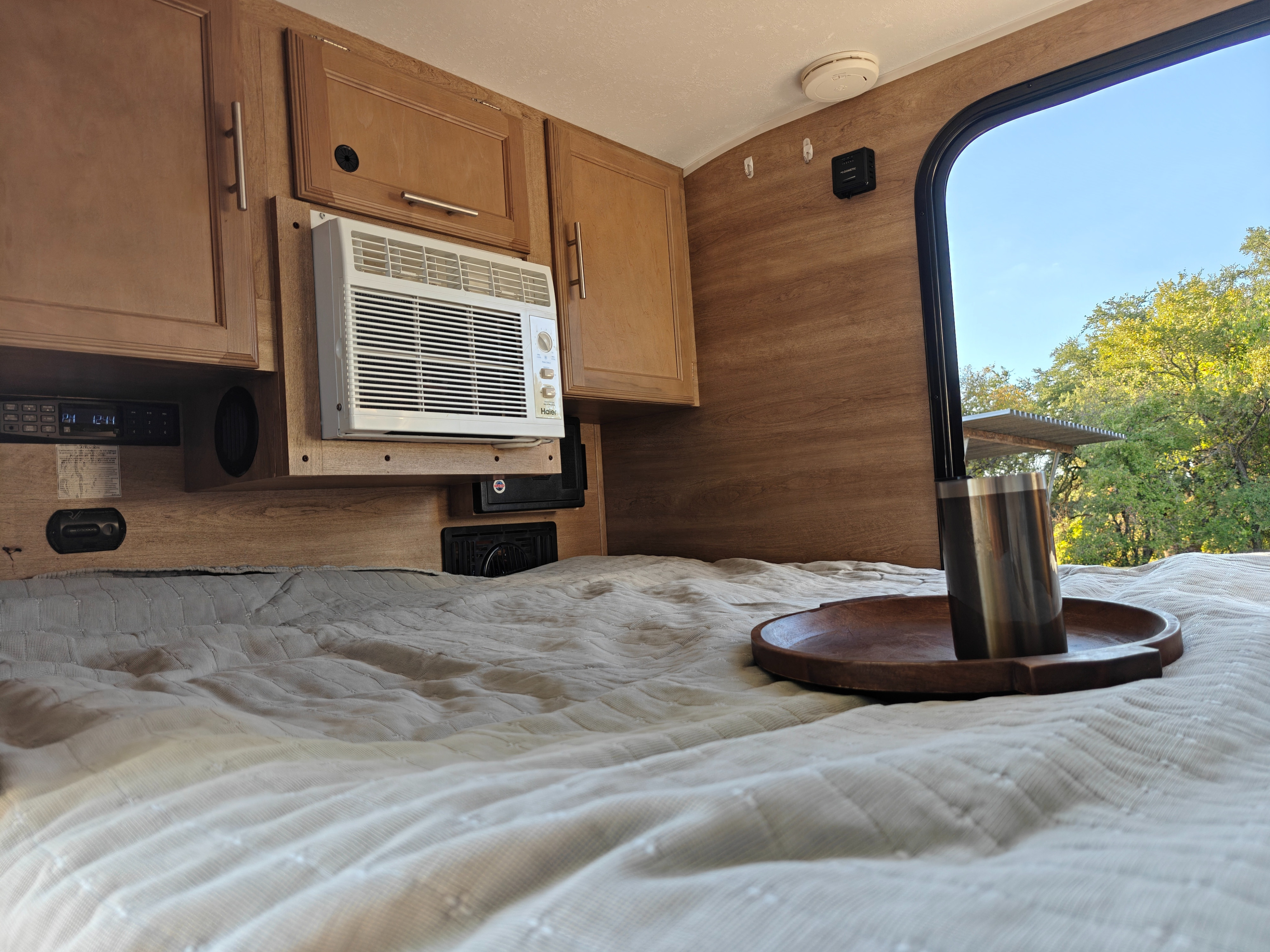 Cozy RV rental bedroom featuring a comfy bed, AC, wooden cabinets, and a refreshing nature view from the window.. Braxton Creek Bushwhacker 2021