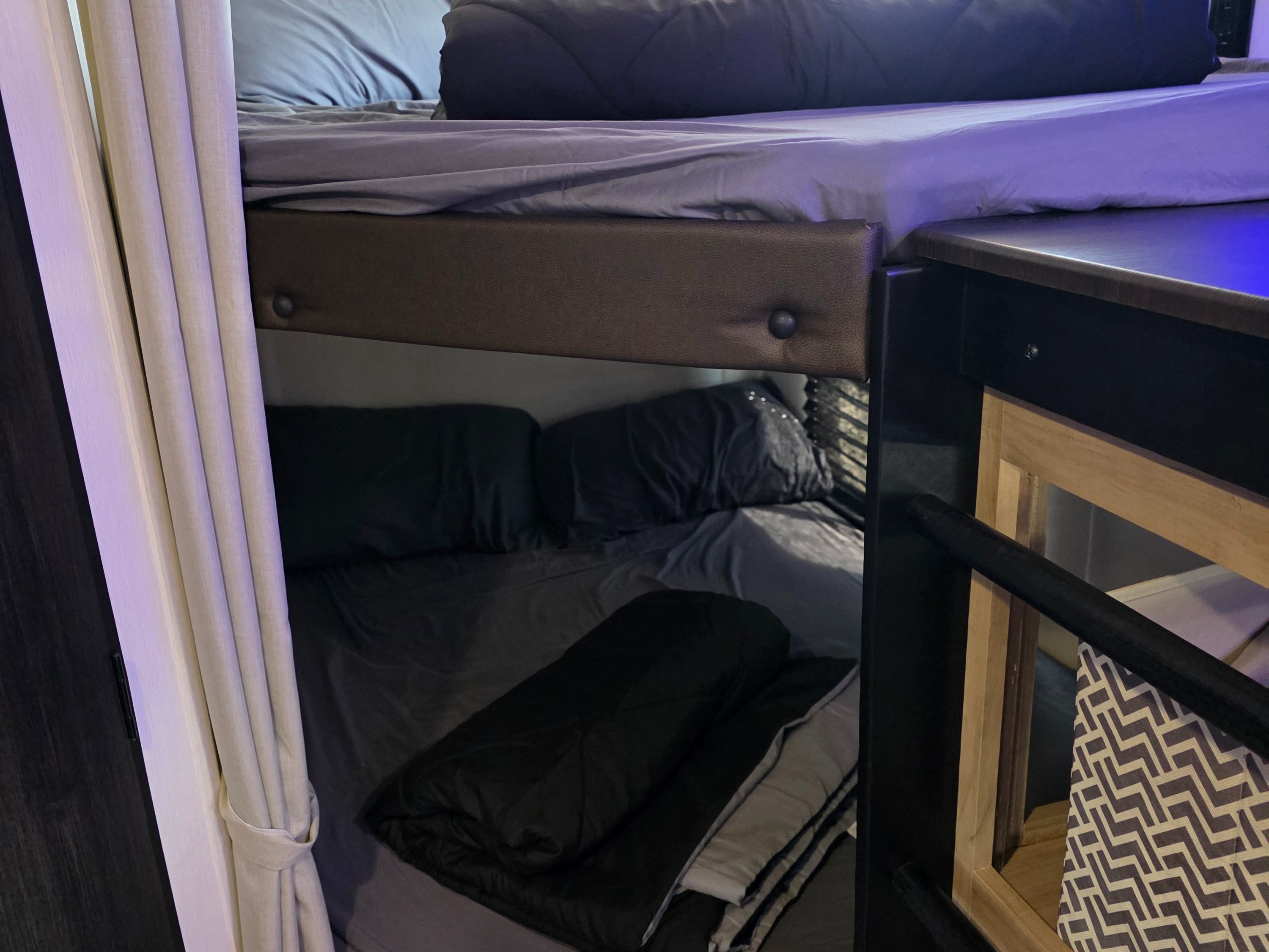 Compact bunk beds with gray bedding and privacy curtains inside an RV rental, providing cozy sleeping space for travel.. Forest River Cherokee Grey Wolf 26KF 2026